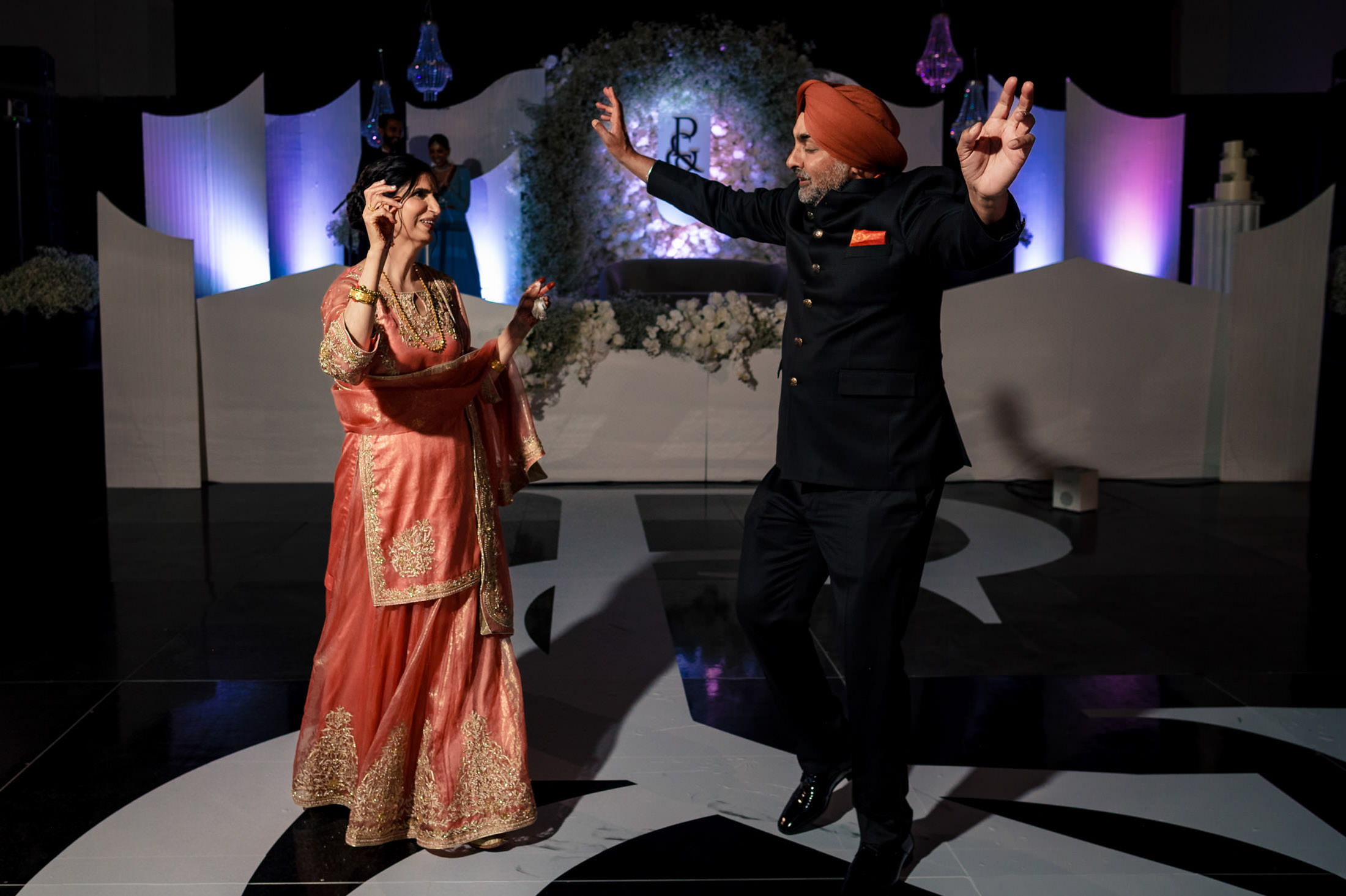 A couple joyfully dances at a Winnipeg wedding, wearing traditional and formal attire.