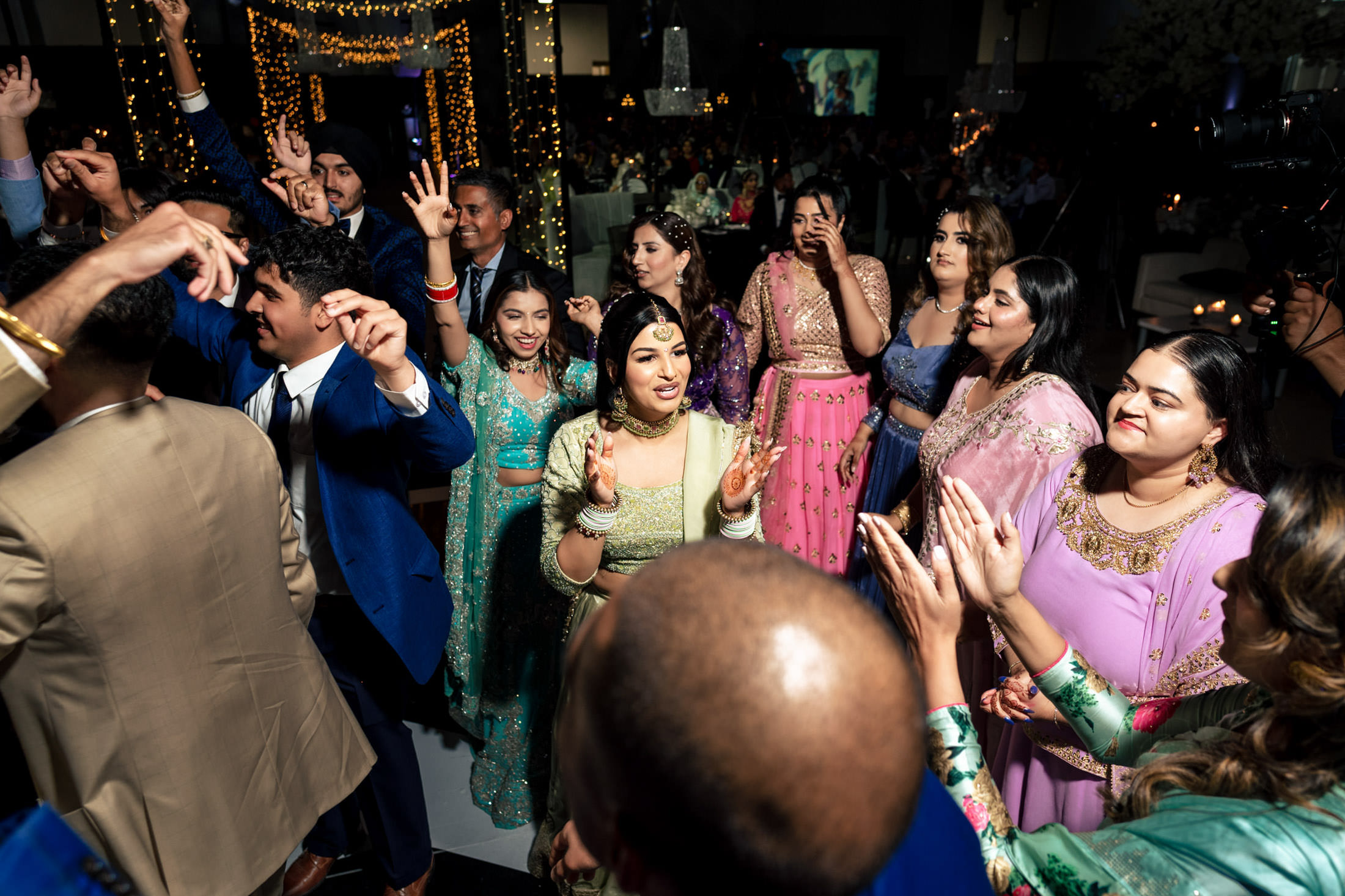 People dancing joyfully at a Winnipeg wedding, wearing colorful traditional attire.