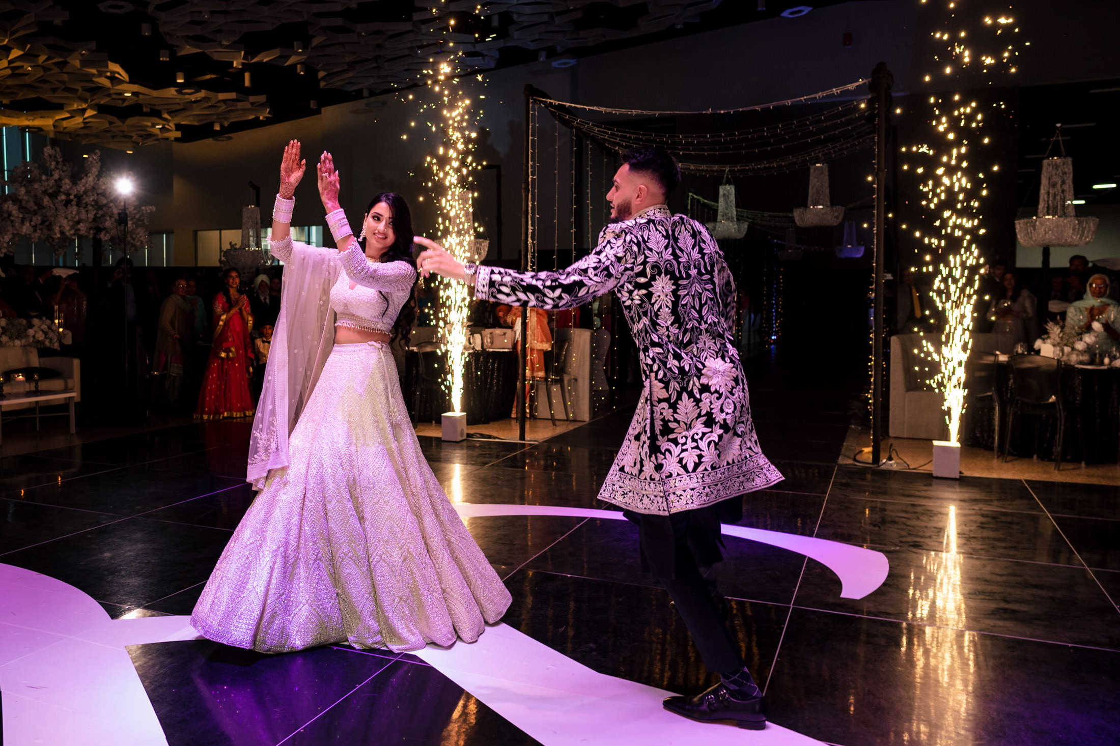A couple dances joyfully under sparklers at a festive Winnipeg wedding.