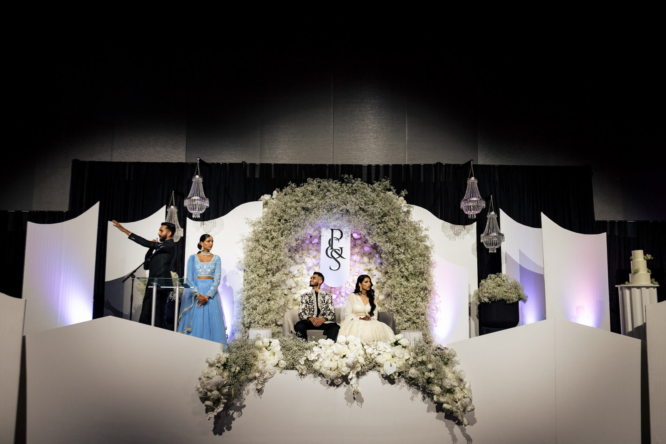 Couple on stage with floral arch, elegant decor, set for a Winnipeg wedding celebration.