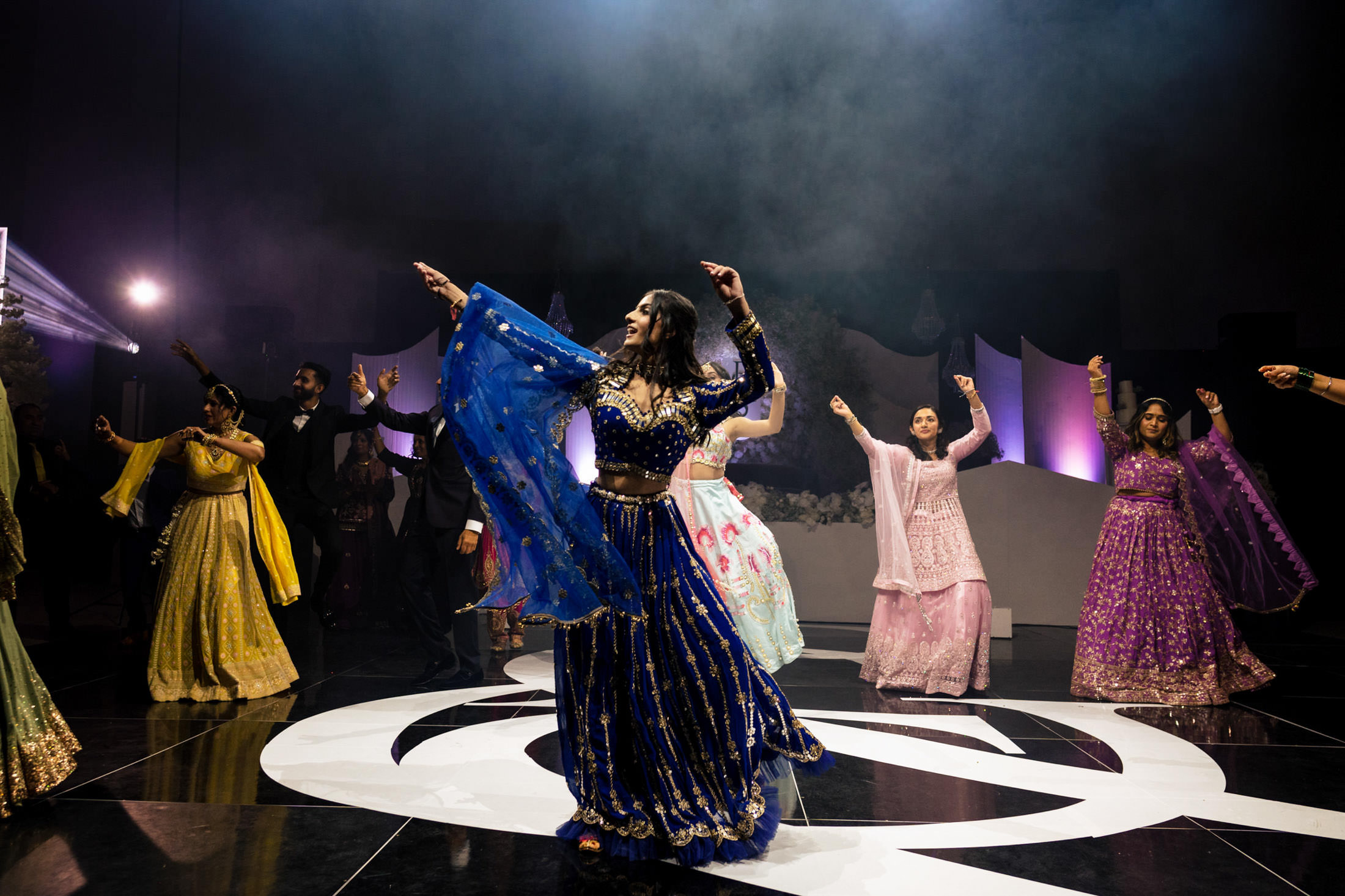 Dancers in colorful traditional attire enliven a Winnipeg wedding stage with dramatic lighting.