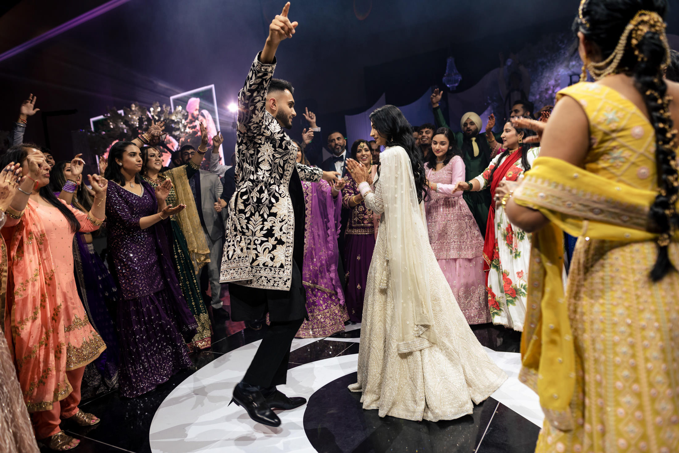 A couple dances at a lively Winnipeg wedding, surrounded by colorful traditional attire.