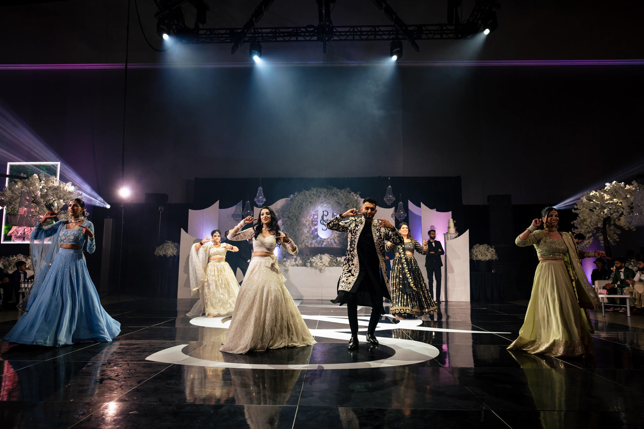 People in formal attire dance on a stage at an elegant Winnipeg wedding.