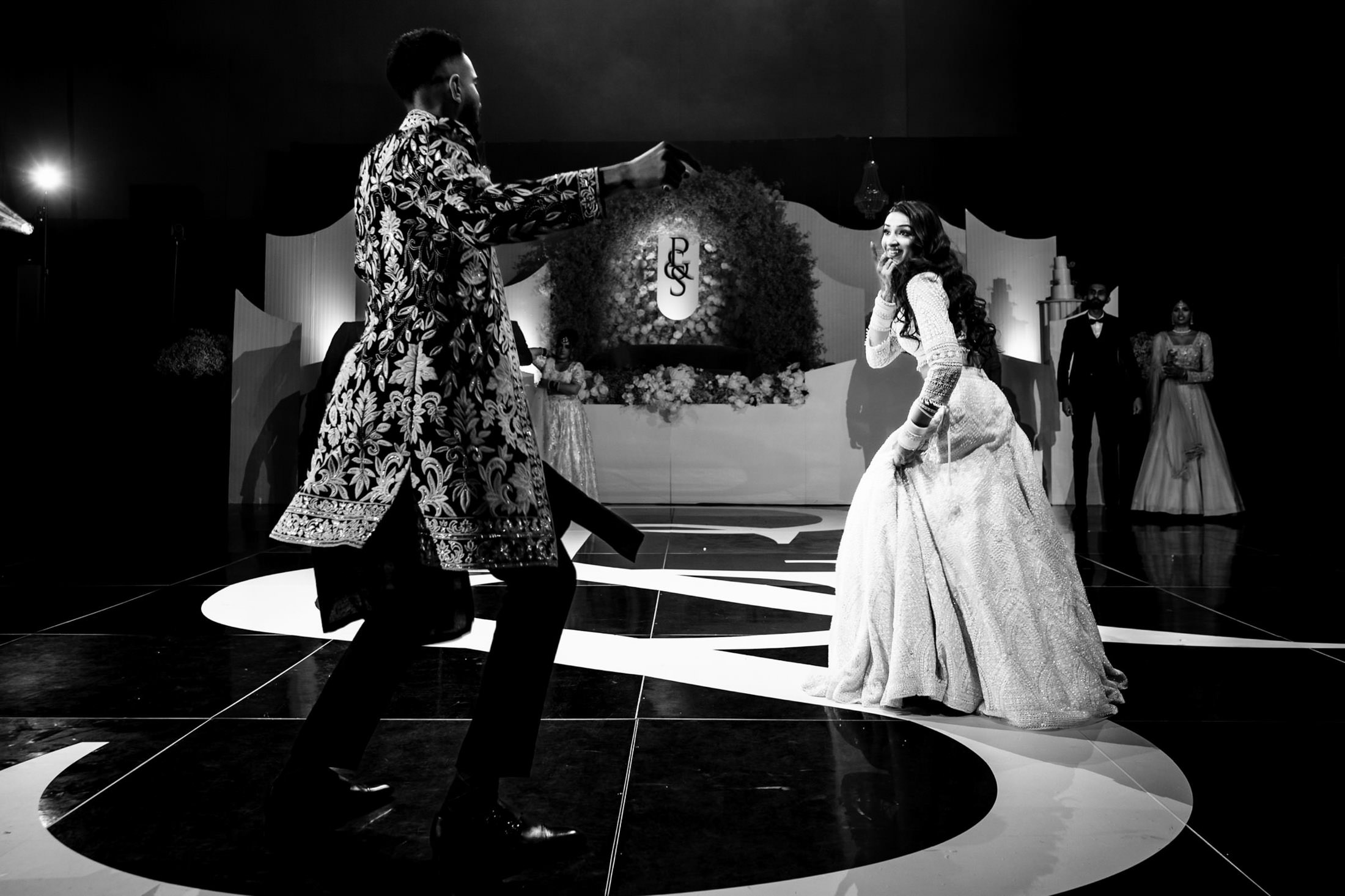 Couple dancing joyfully in elegant attire at a Winnipeg wedding on a decorated stage.