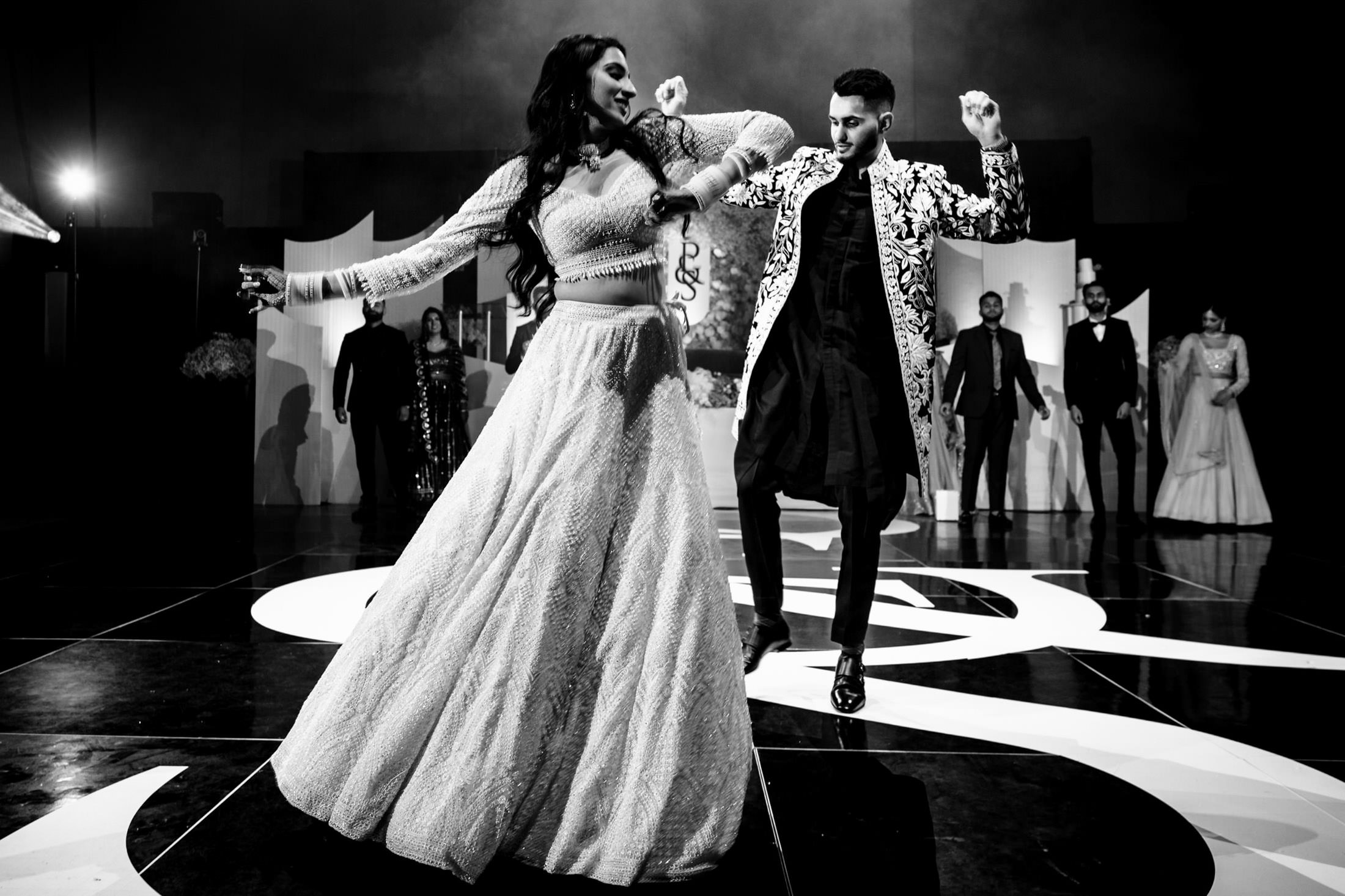 Dancing joyfully in elegant attire on a Winnipeg wedding stage.