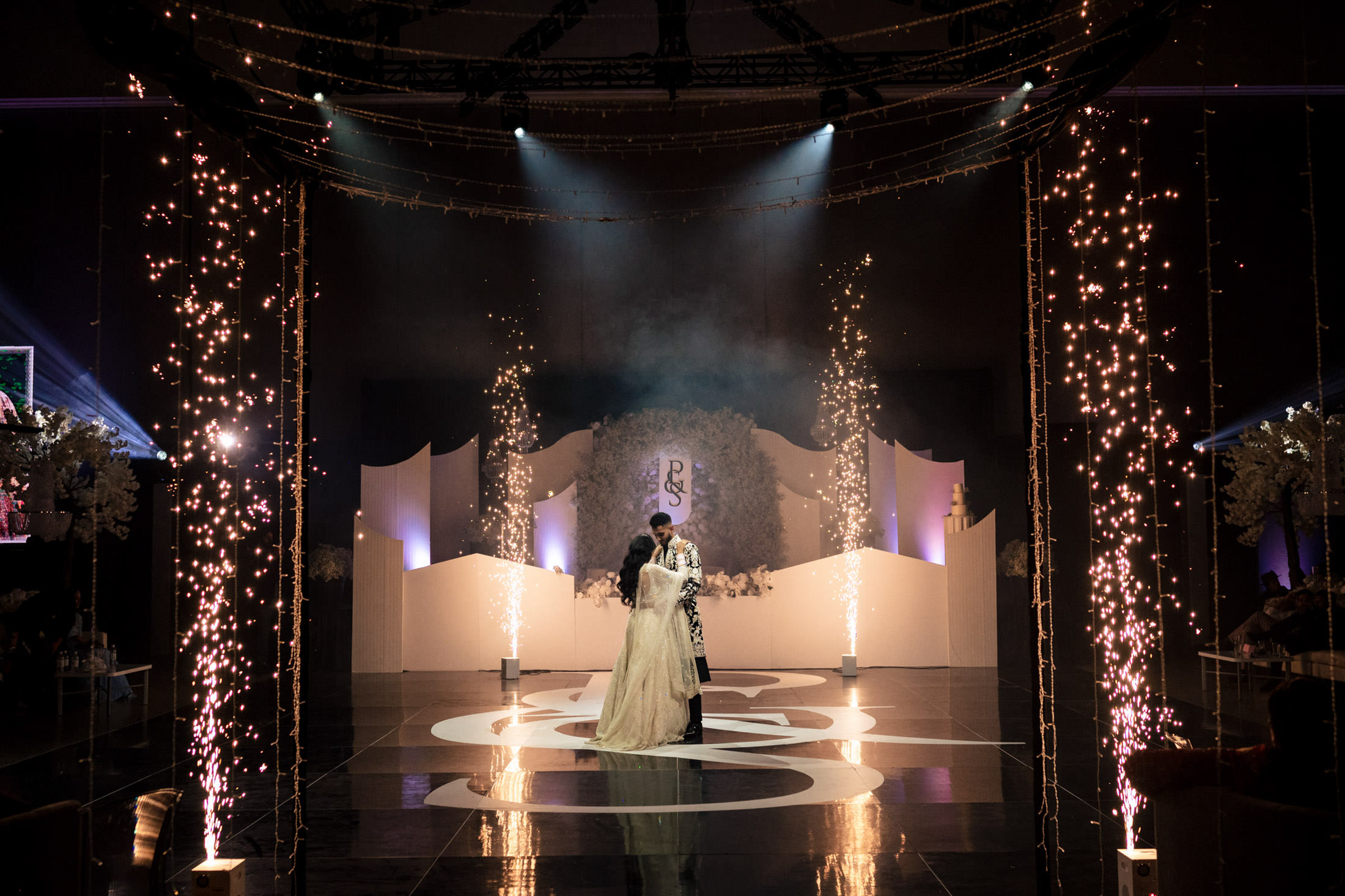 Couple dancing on a decorated Winnipeg wedding stage with sparklers and floral arrangements.