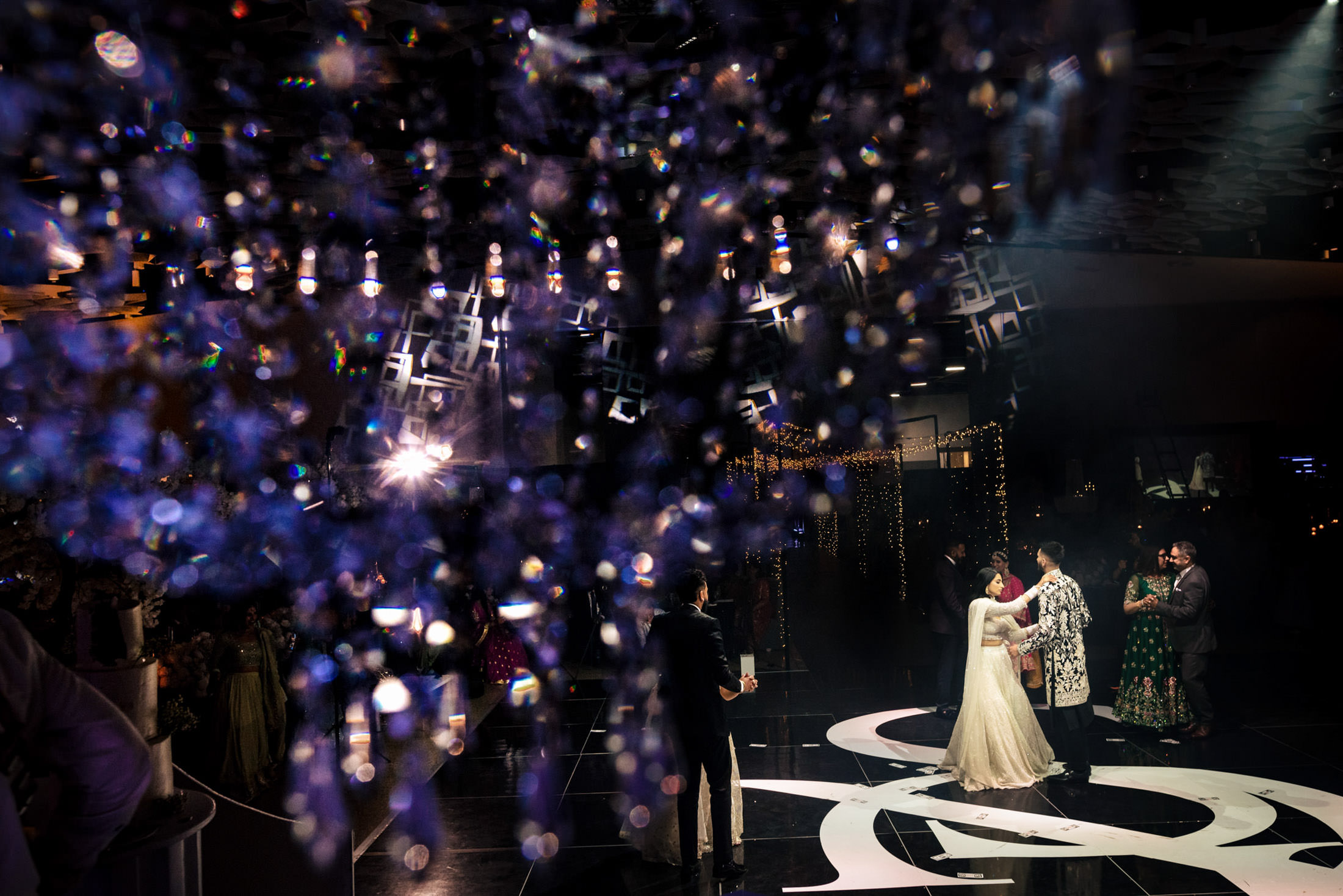 A couple dances at a Winnipeg wedding, guests and ornate lighting fill the background.