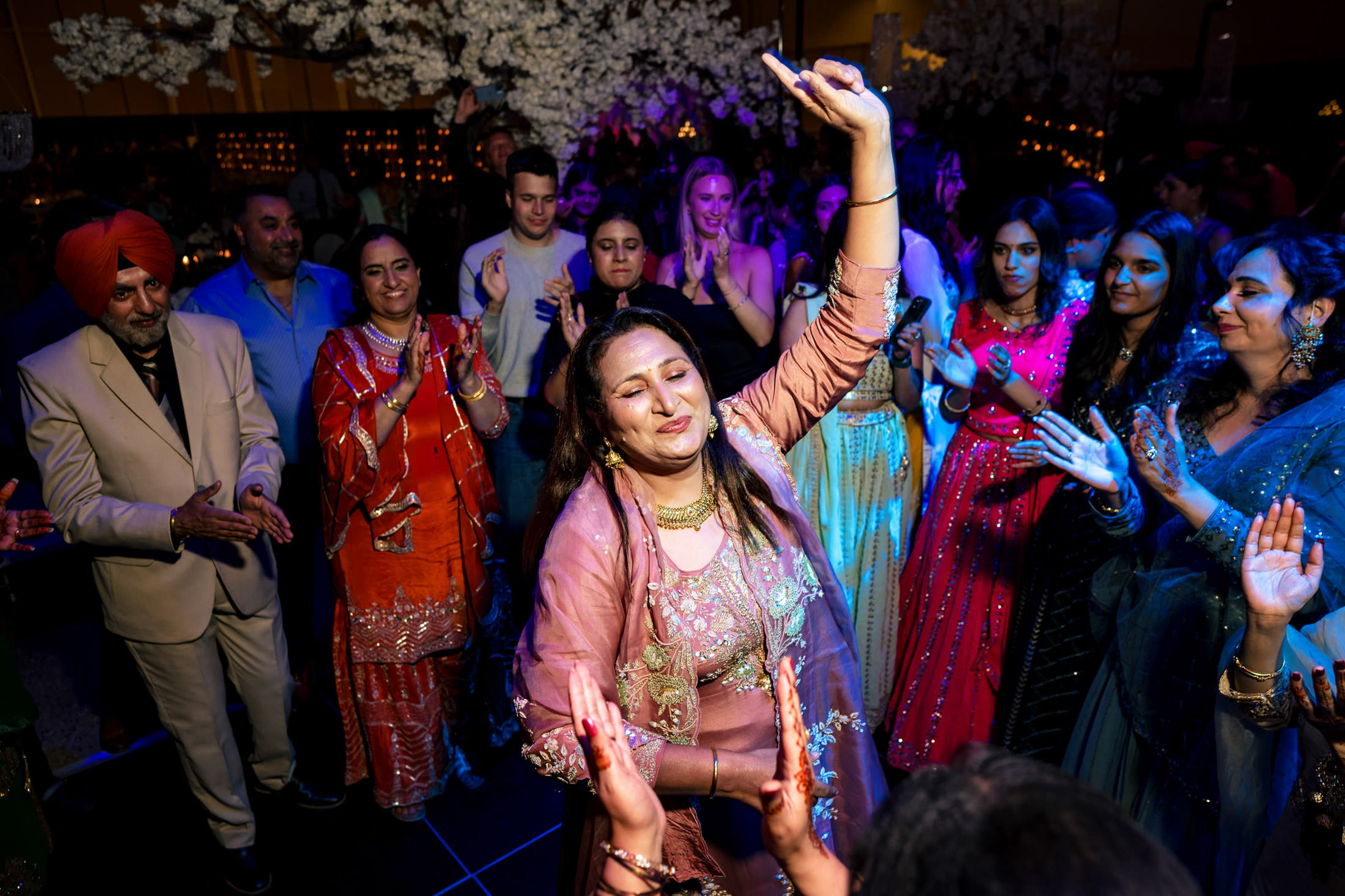 Woman dancing joyfully in vibrant traditional attire at a festive Winnipeg wedding.