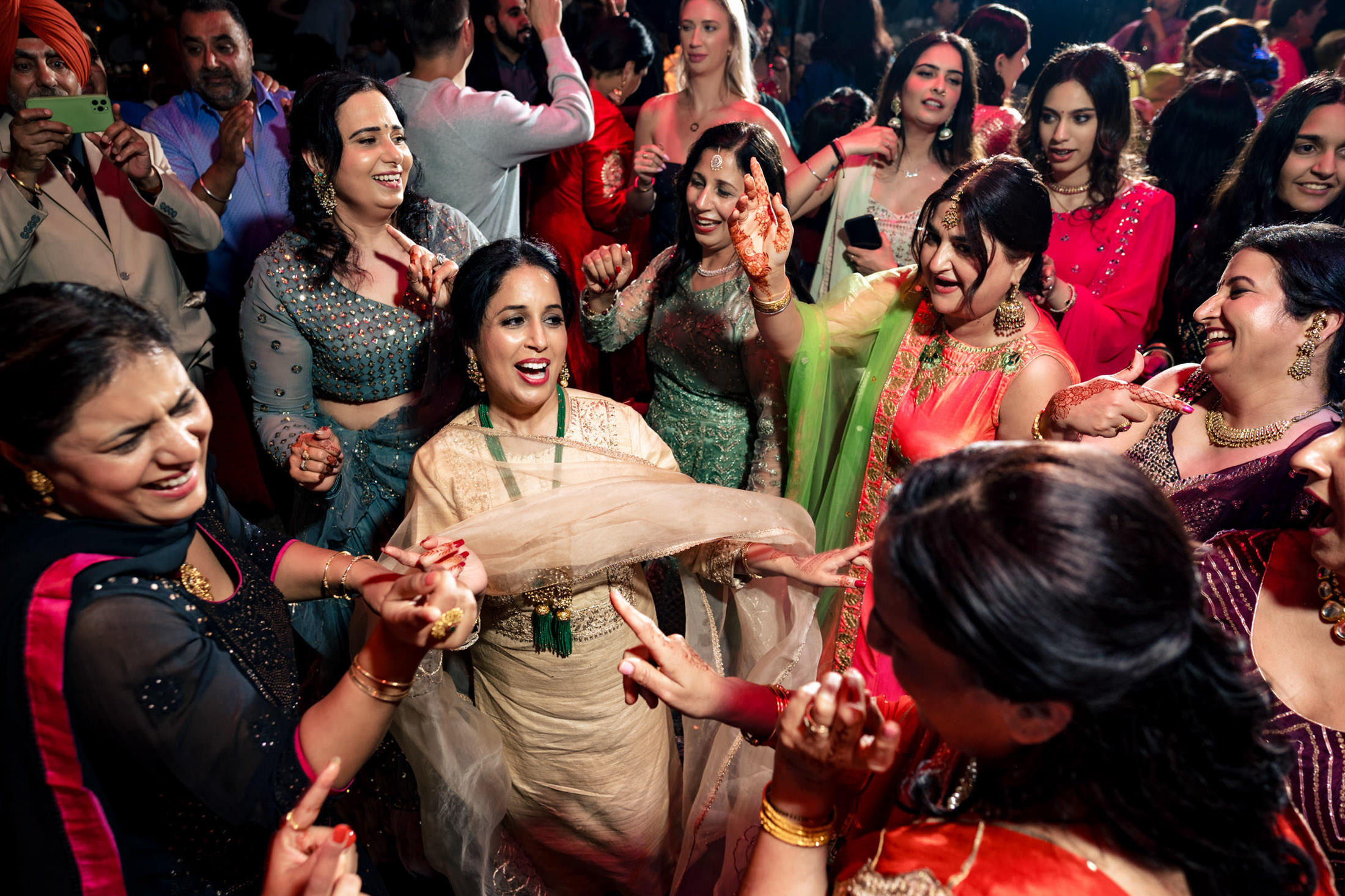 People joyfully dancing at a colorful Winnipeg wedding, wearing vibrant traditional attire.
