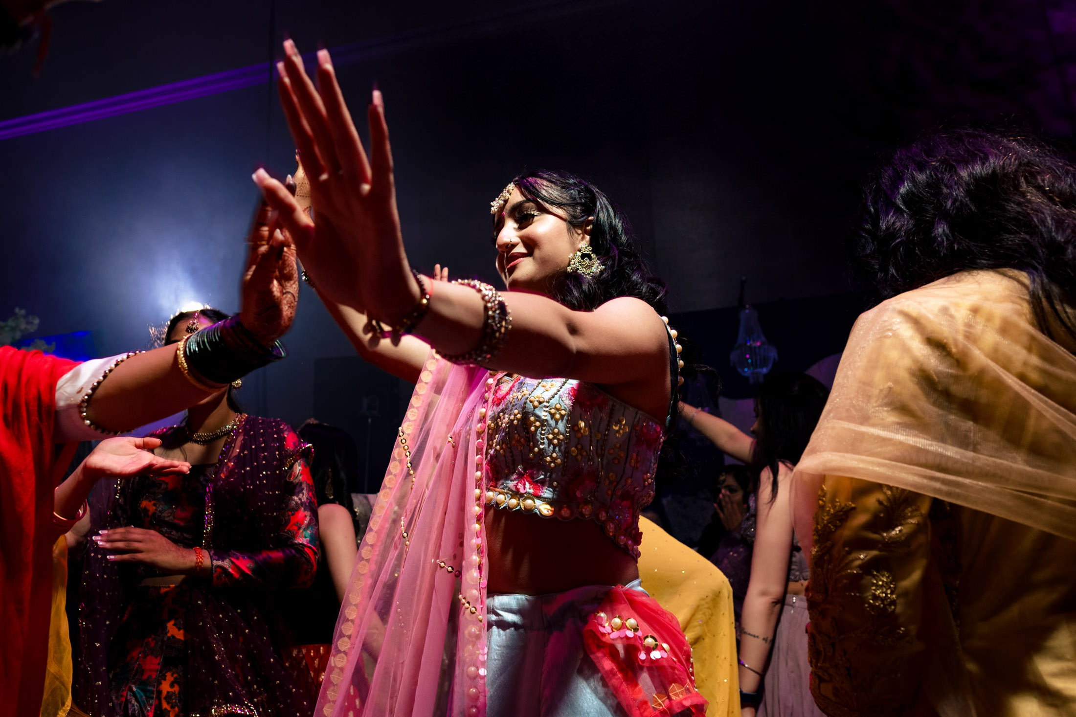 People dancing energetically in colorful attire at a vibrant Winnipeg wedding.
