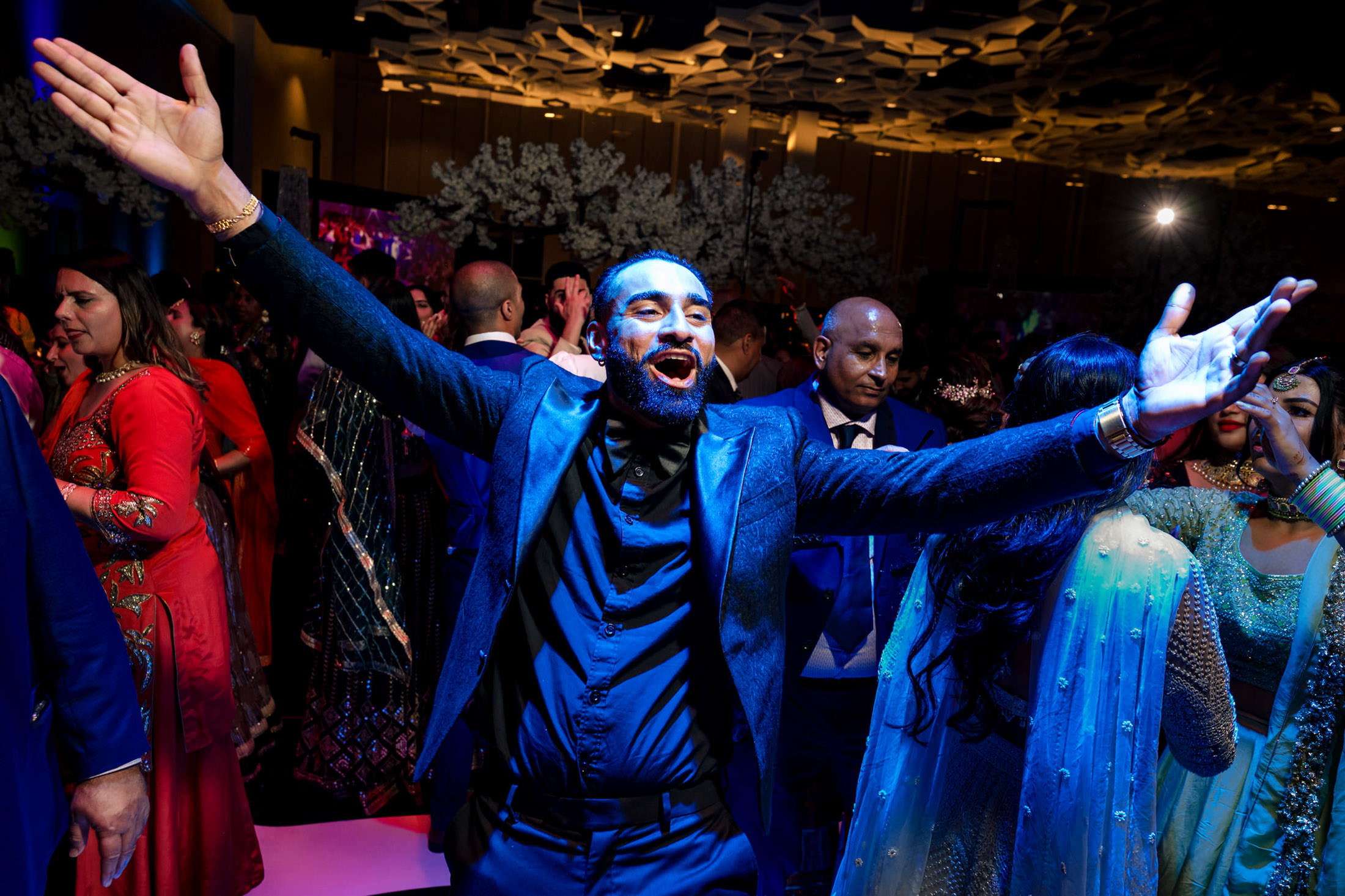Person joyfully dancing at a lively Winnipeg wedding, surrounded by a colorful crowd.