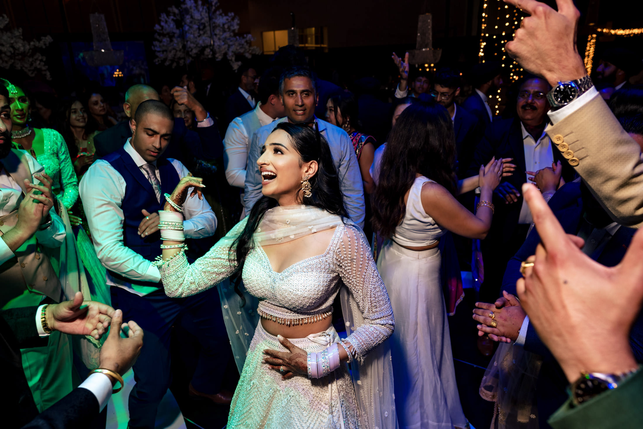 Woman in traditional attire dancing at a lively Winnipeg wedding with a crowd around her.