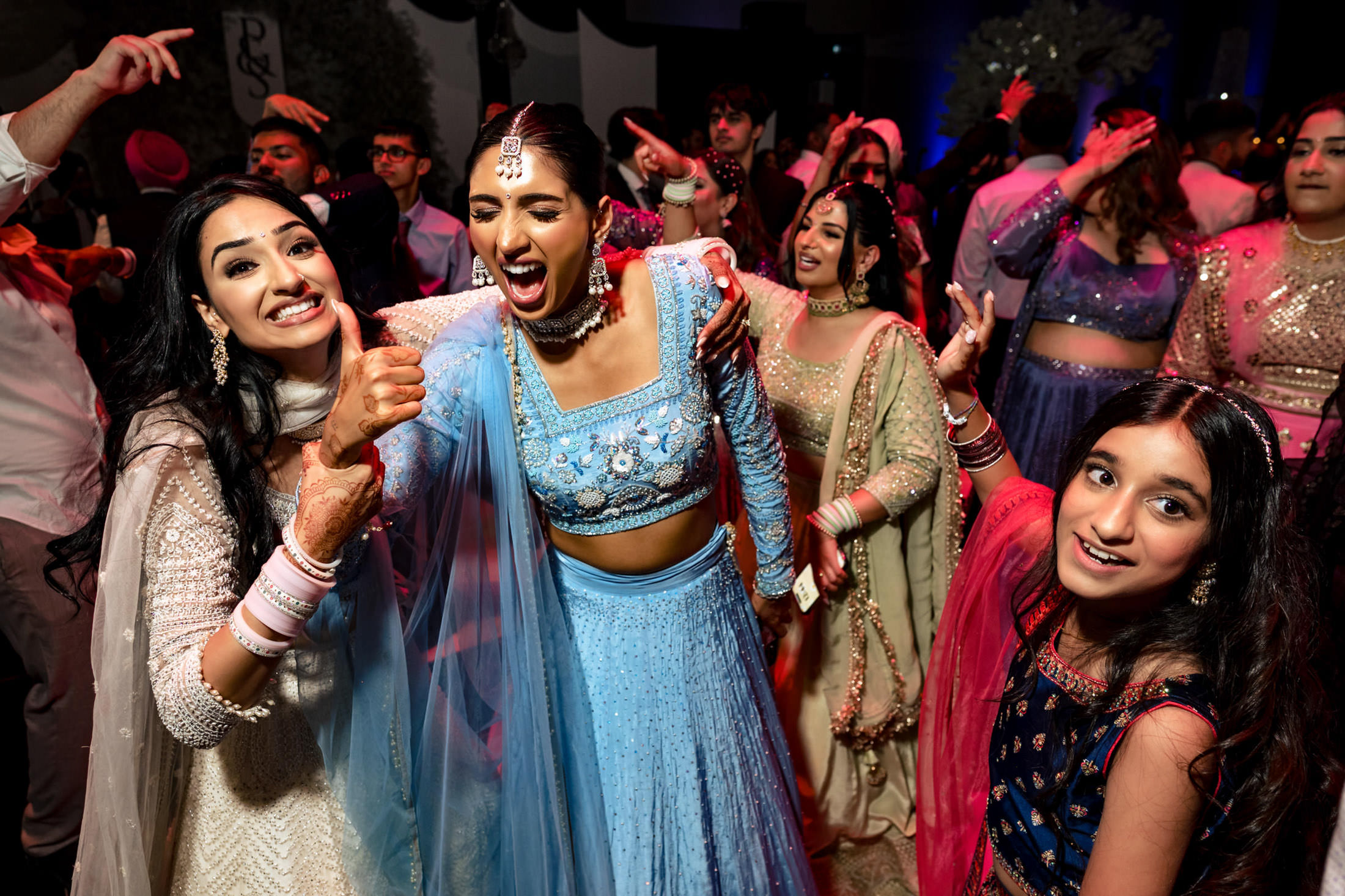 People joyfully dancing at a colorful Winnipeg wedding, wearing vibrant traditional attire.