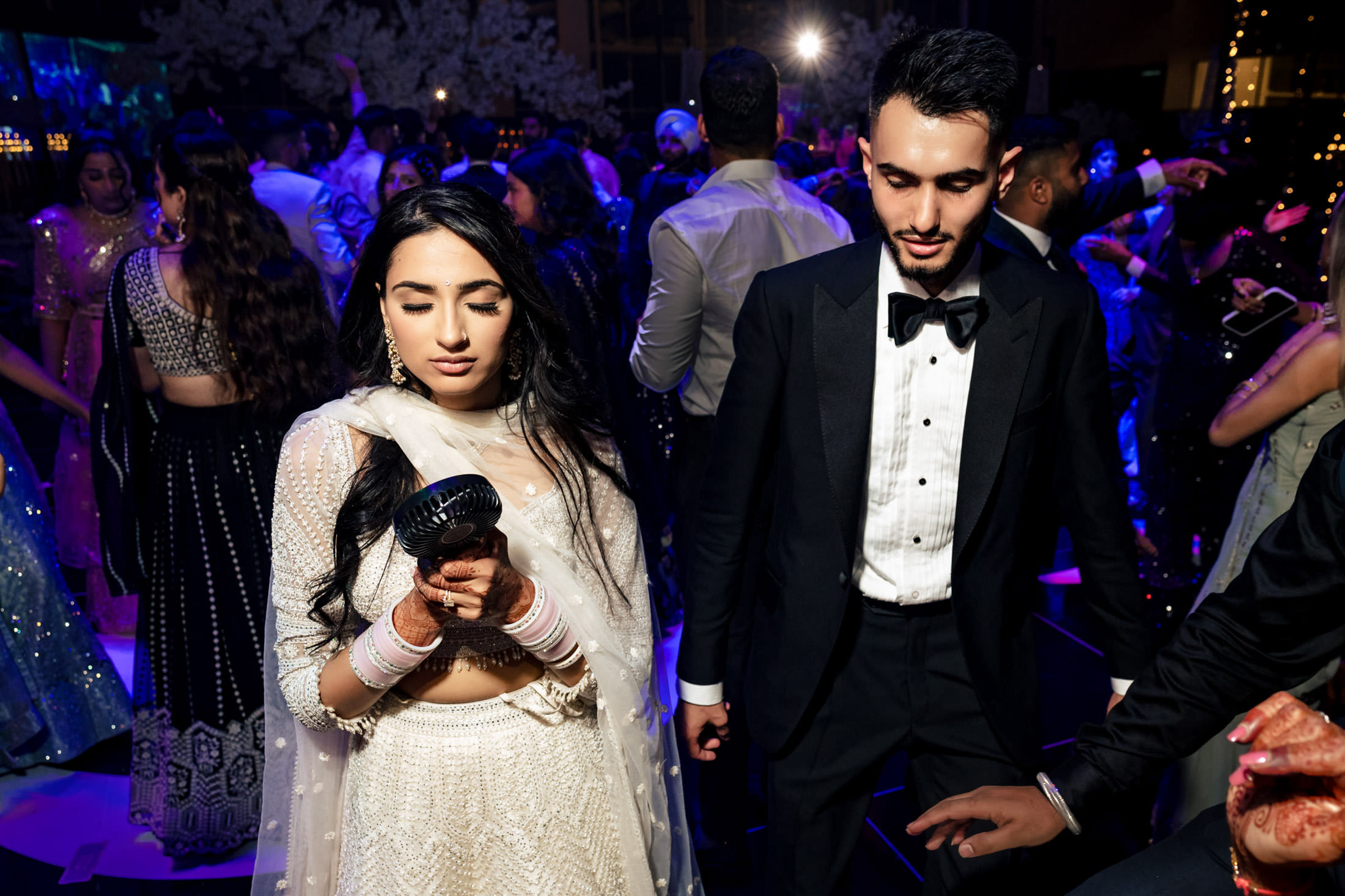 A couple in a white dress and tuxedo dance at a colorful Winnipeg wedding.