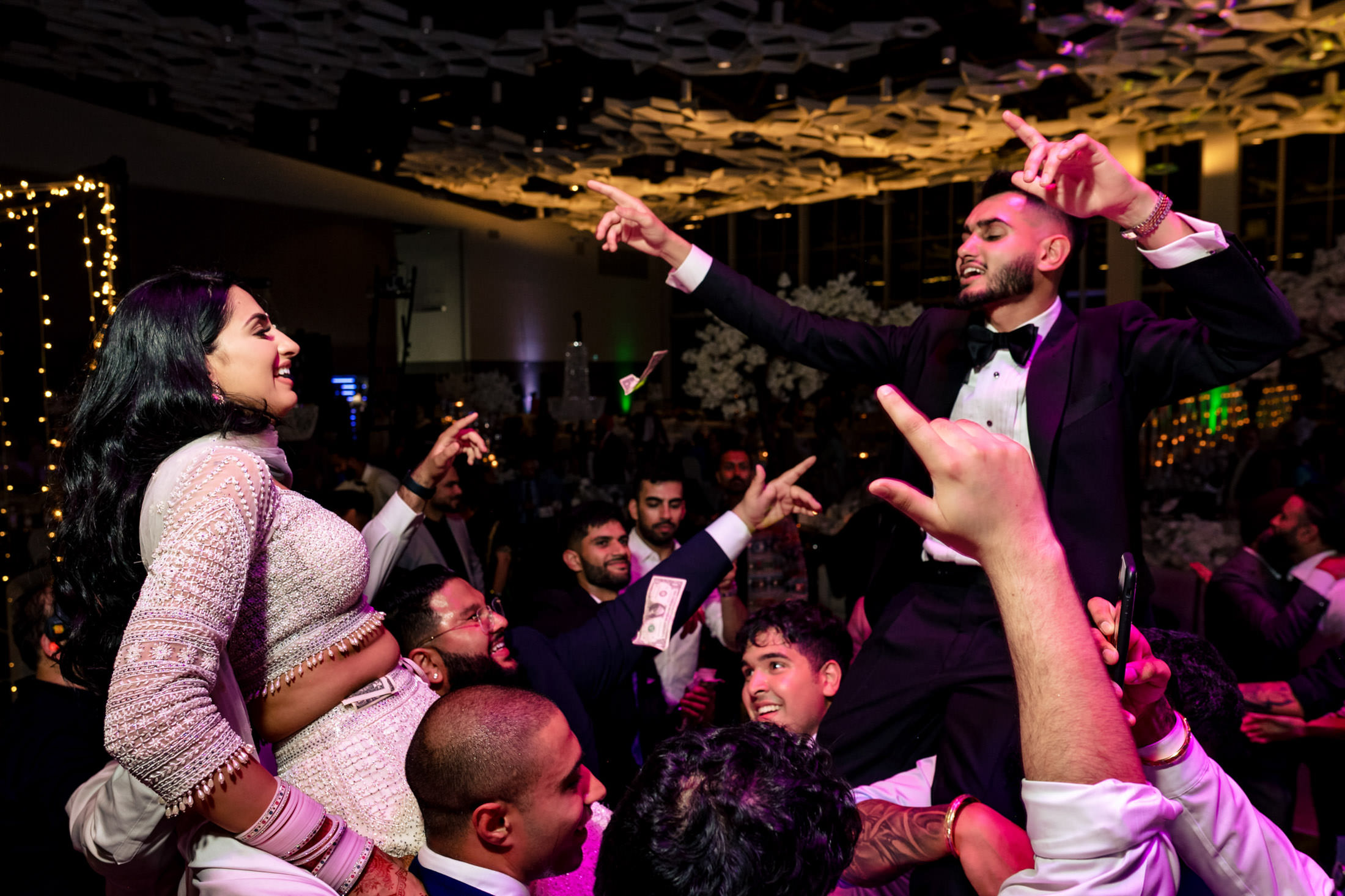 Guests celebrating at a Winnipeg wedding, two people are lifted on shoulders, dancing and smiling.
