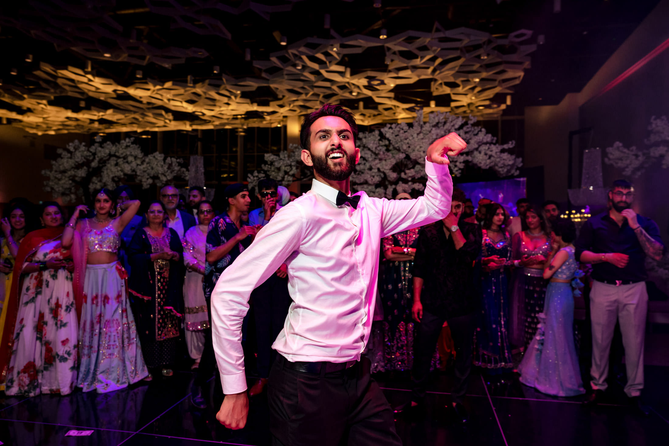 A man dancing energetically at a lively Winnipeg wedding, with a crowd watching.