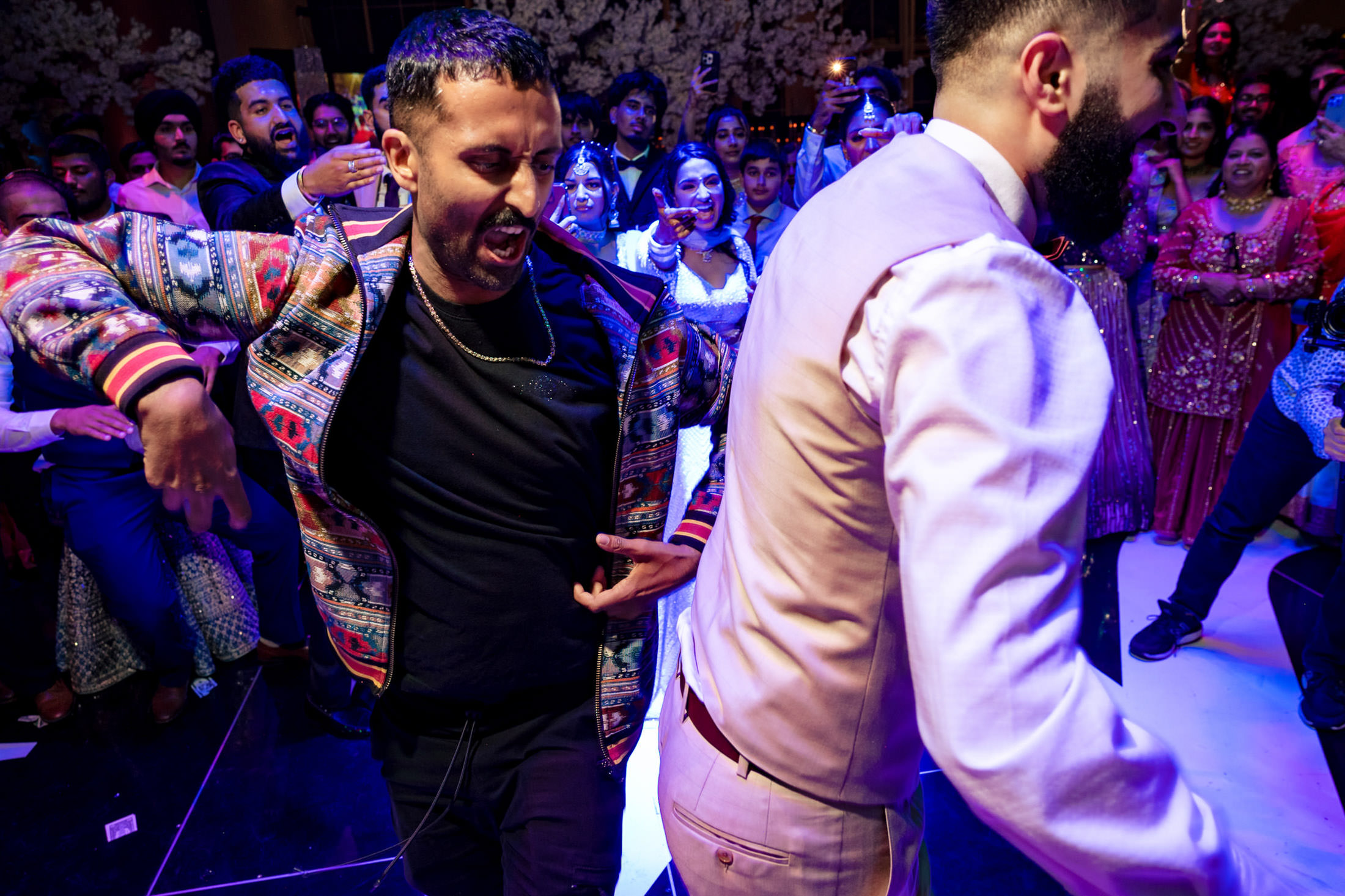 Two people dancing energetically at a lively Winnipeg wedding with onlookers.