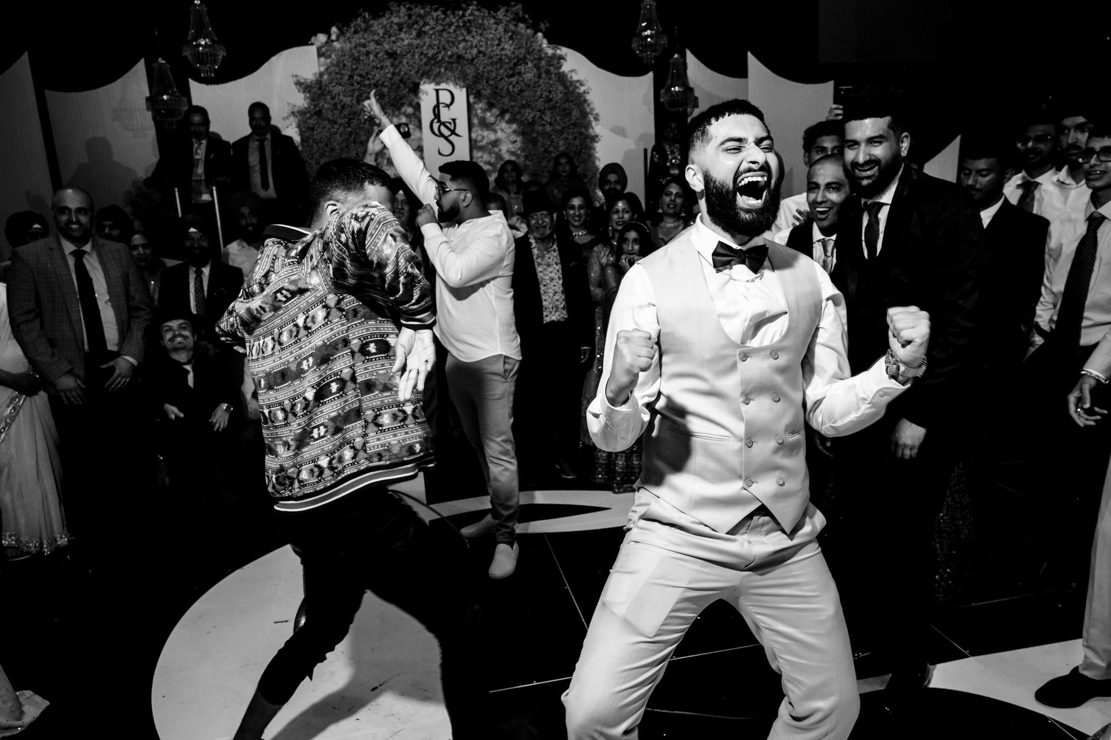Energetic dancing at a Winnipeg wedding, with guests cheering and clapping in the background.