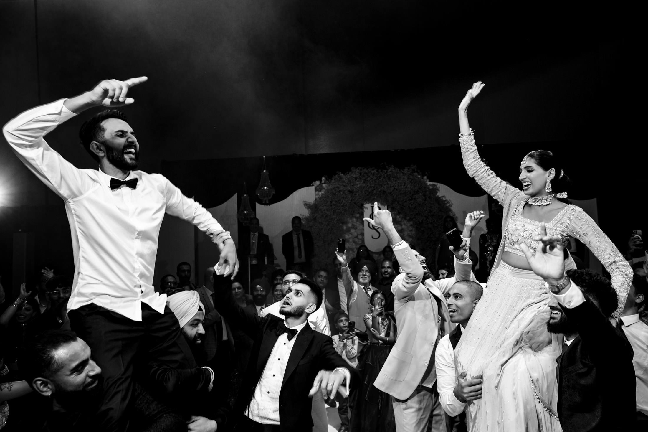 A joyful couple dancing on shoulders at a lively Winnipeg wedding celebration.