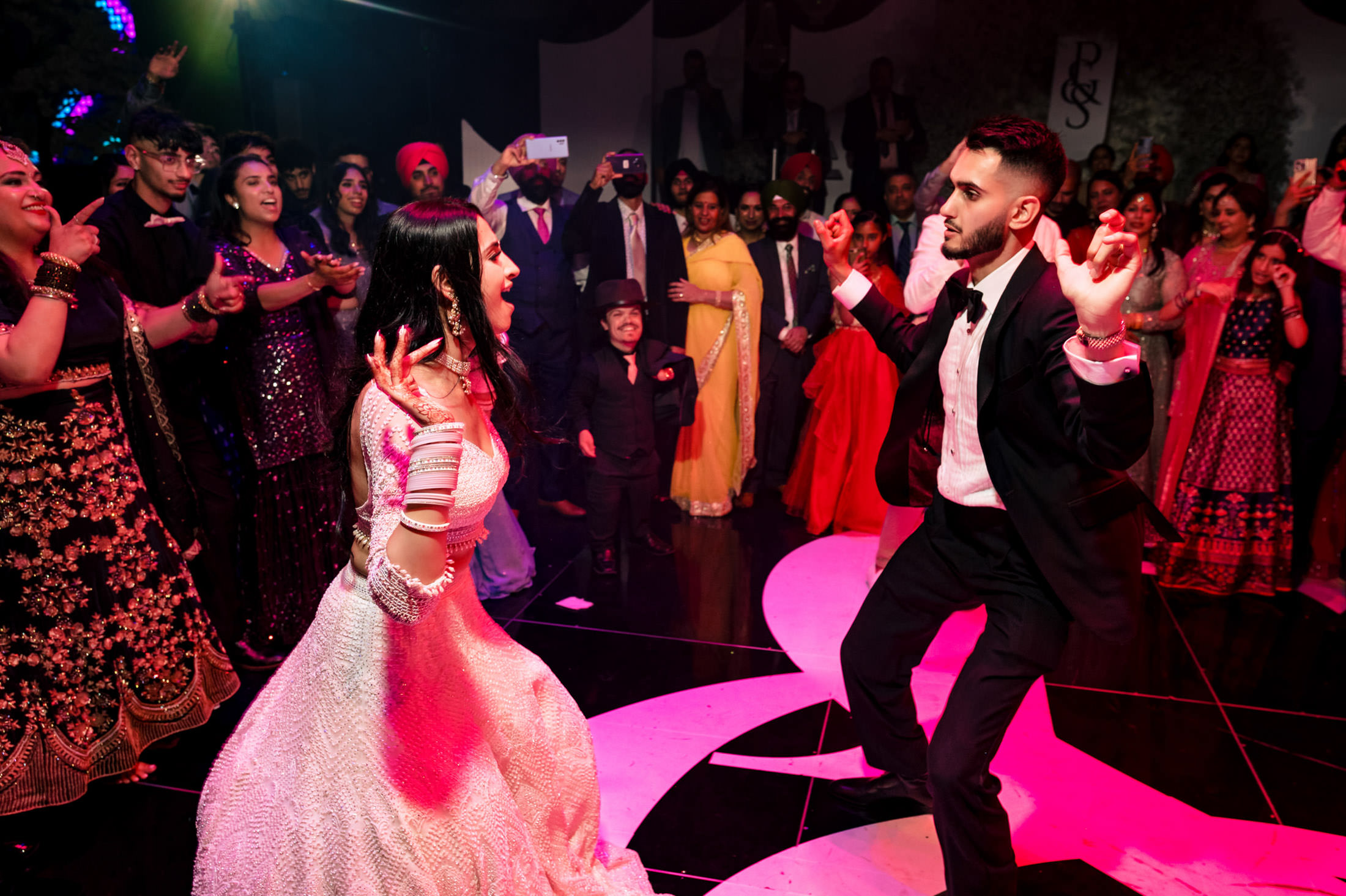 Energetic bride and groom dancing at a Winnipeg wedding, cheered on by excited guests.