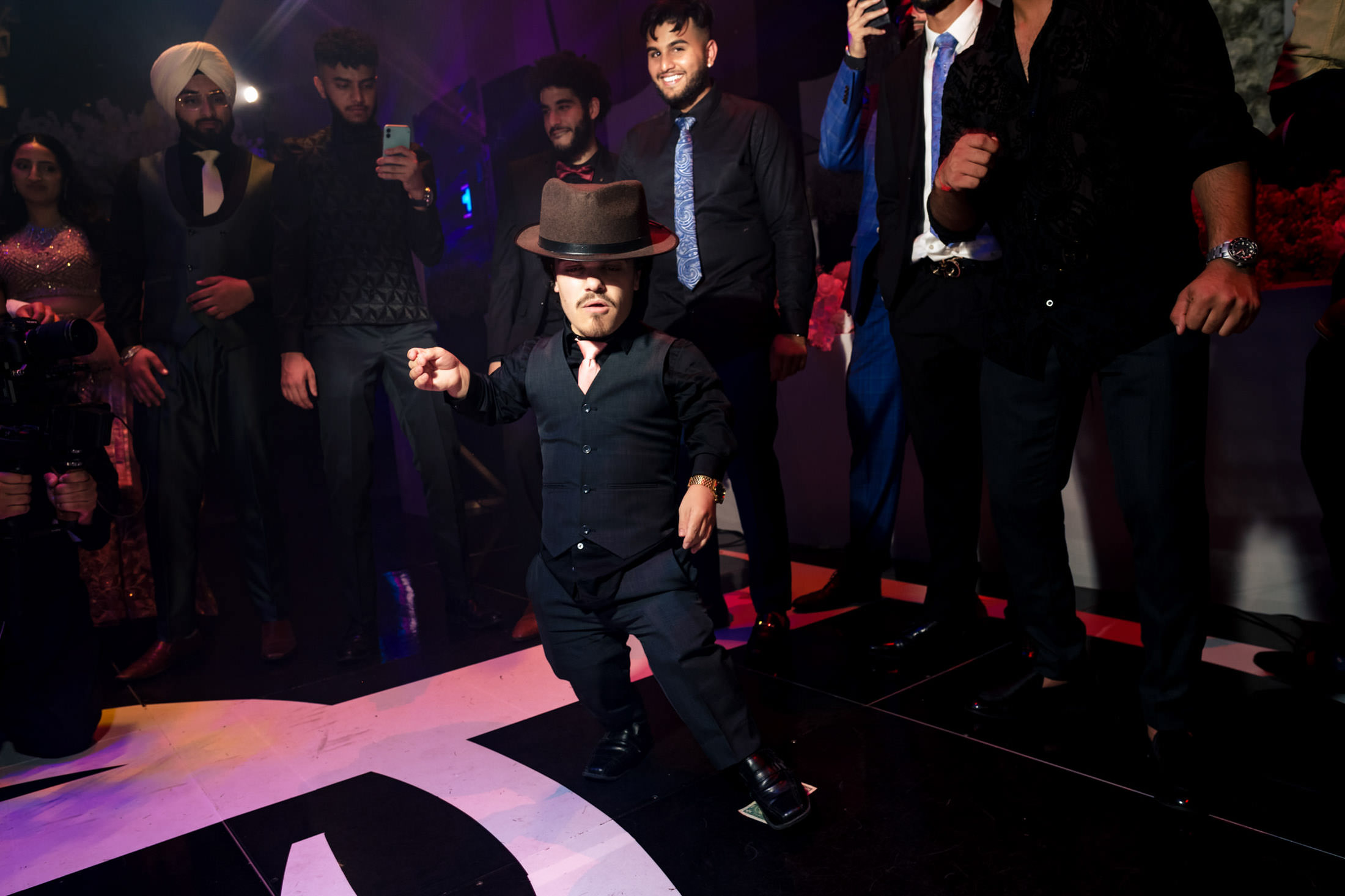 A person energetically dances on stage at a Winnipeg wedding as the group films.