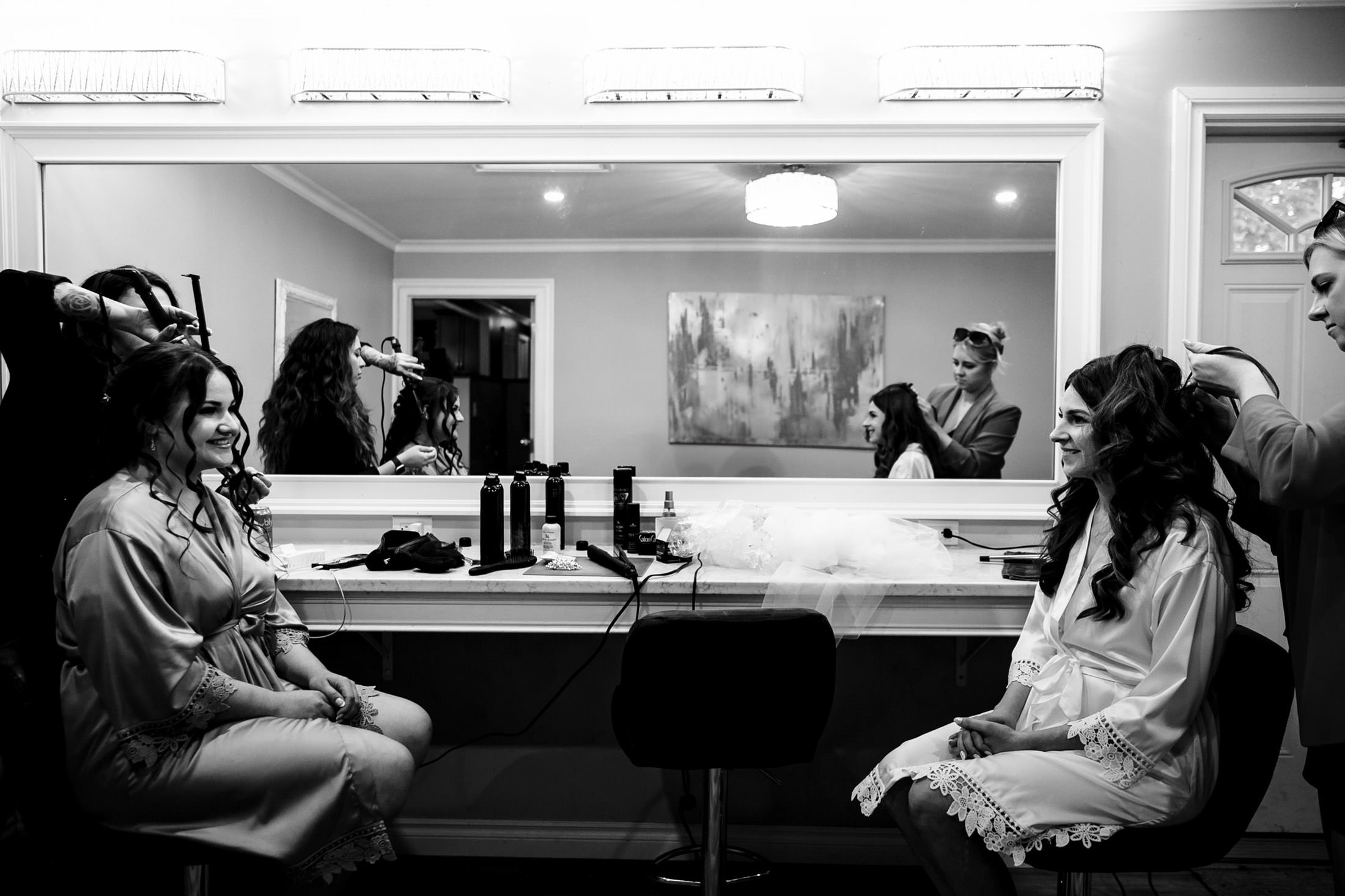 Two women in robes smile at each other, prepping for an Ashgrove Acres wedding.
