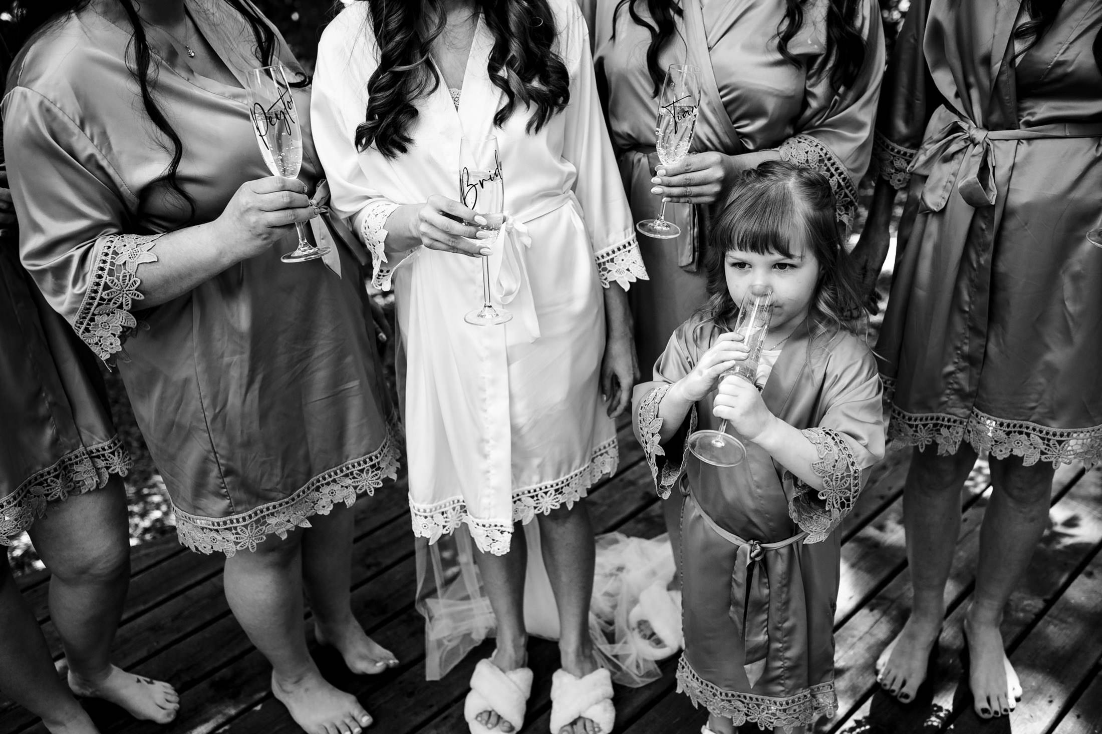 Women and a child in robes holding champagne glasses at an Ashgrove Acres wedding.