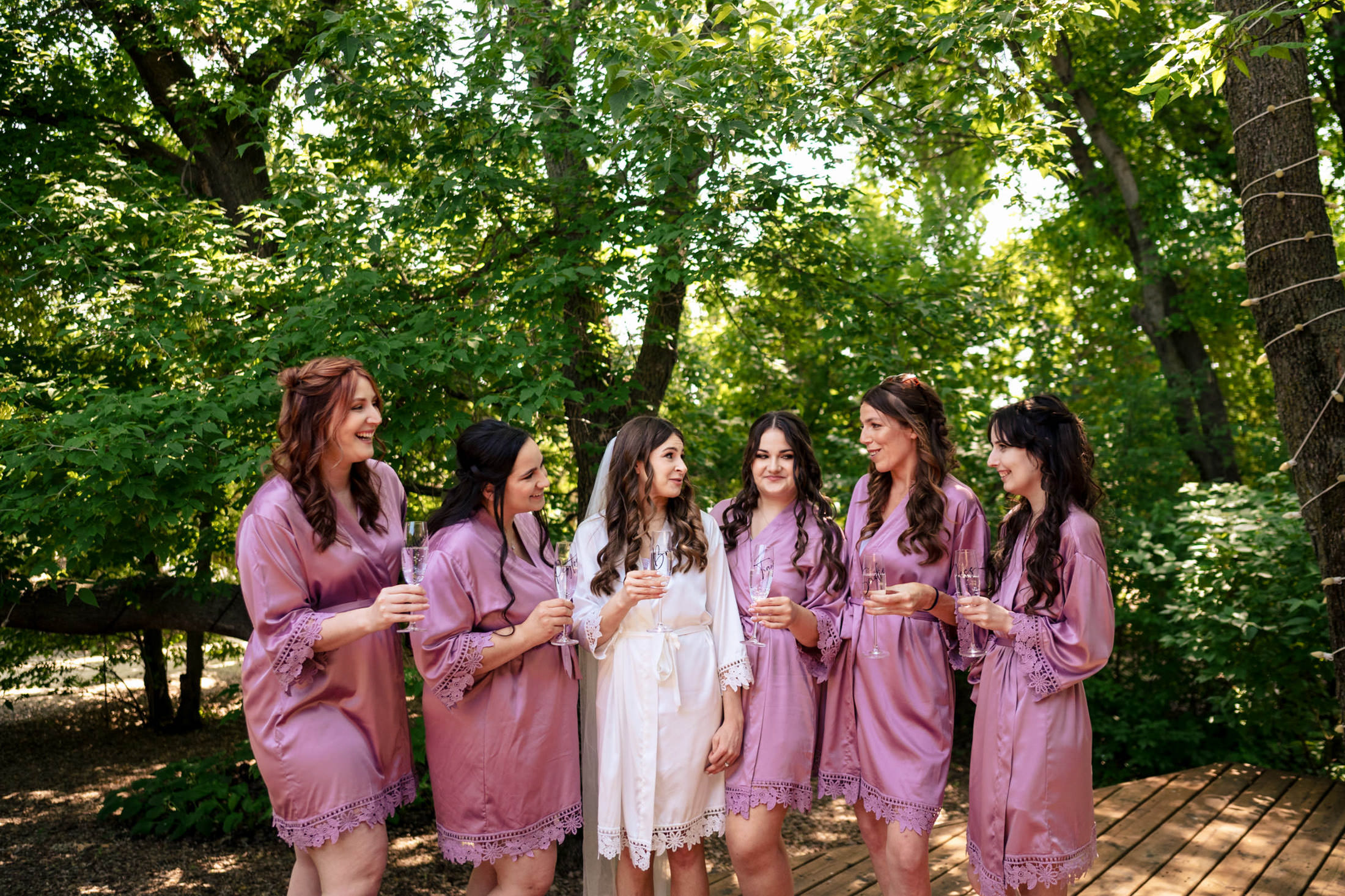Women in robes share a laugh at Ashgrove Acres, surrounded by lush green trees.