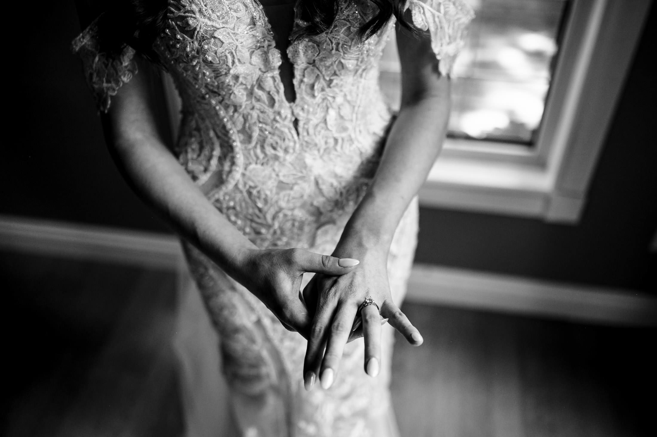 Bride in lace dress, framed by light at an Ashgrove Acres Wedding, touches her ring.