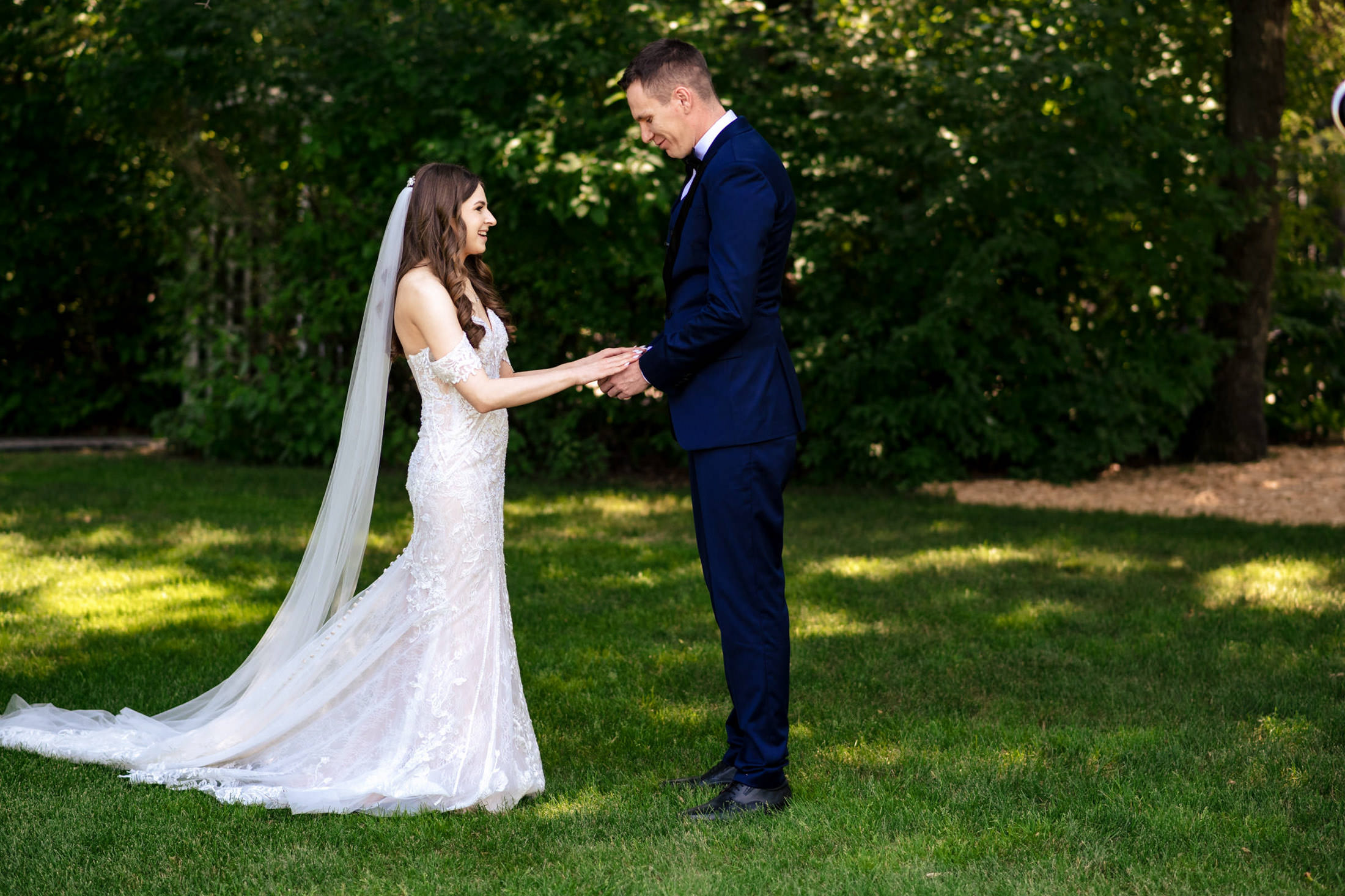A bride and groom smile, holding hands at Ashgrove Acres' garden wedding.