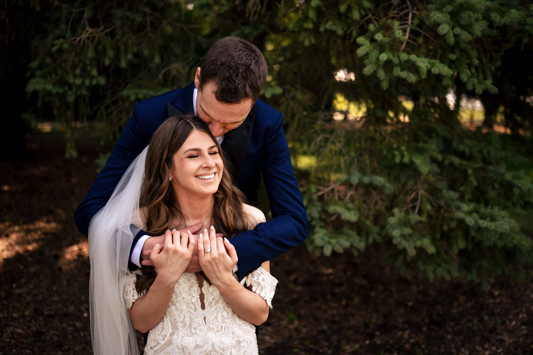 Bride and groom embracing at Ashgrove Acres, with the groom kissing her on the head.