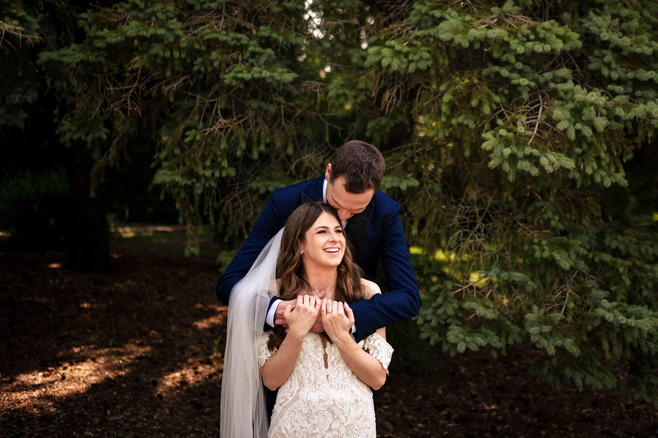 Bride and groom smiling at Ashgrove Acres, with the groom embracing her from behind.