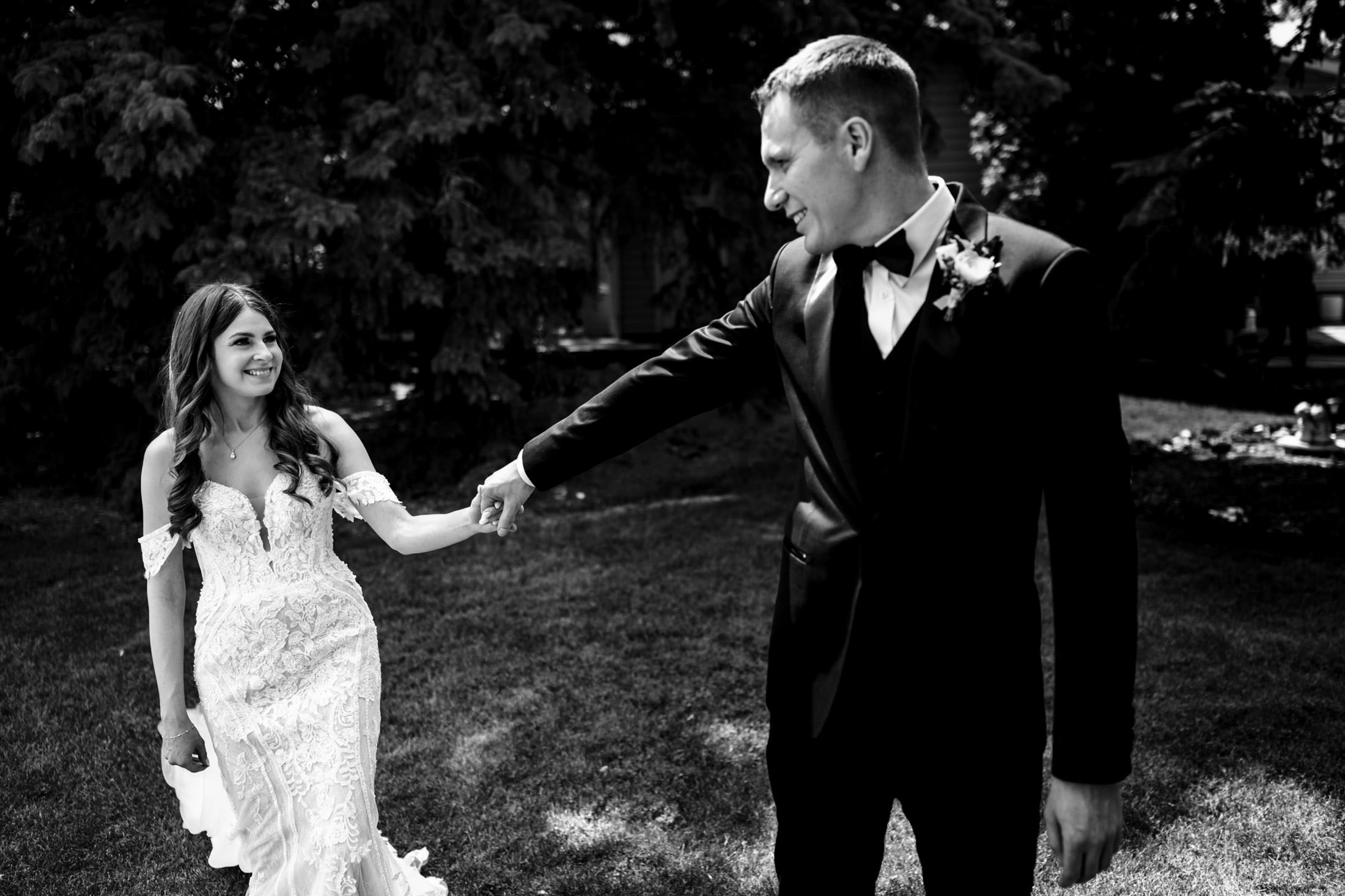 Bride and groom smiling, holding hands outdoors at Ashgrove Acres.