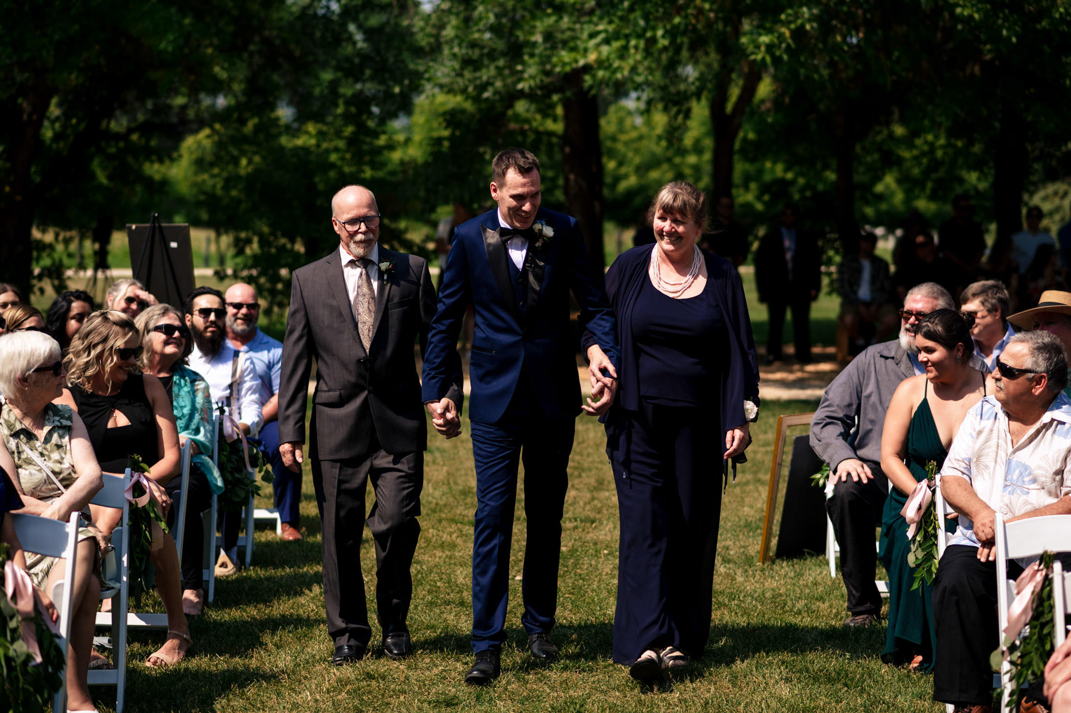 A man in a suit walks with an older couple down the aisle at Ashgrove Acres.