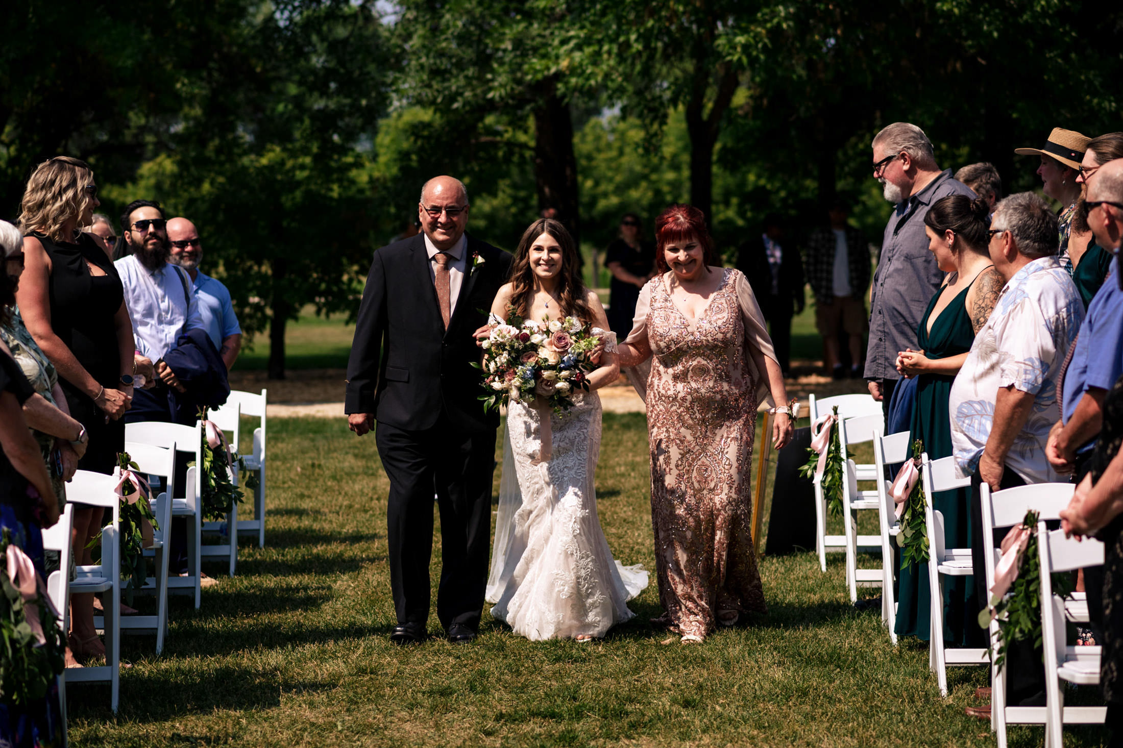 Bride walking down the aisle at Ashgrove Acres Wedding, surrounded by seated guests outdoors.