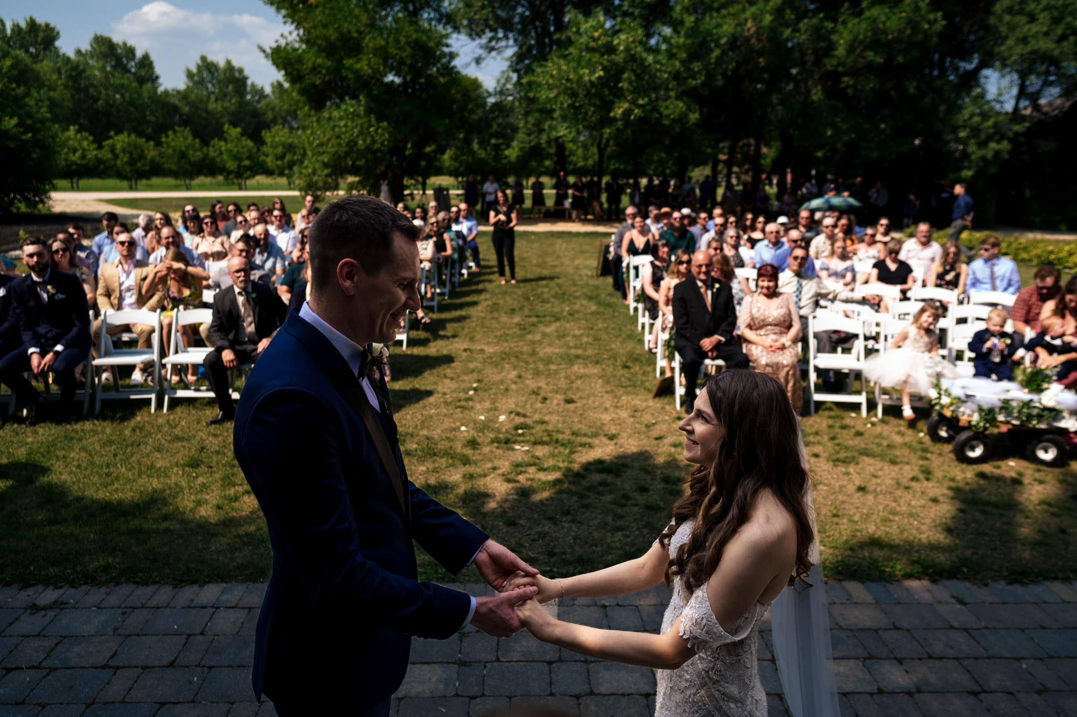 Couple holding hands at Ashgrove Acres Wedding, surrounded by seated guests.