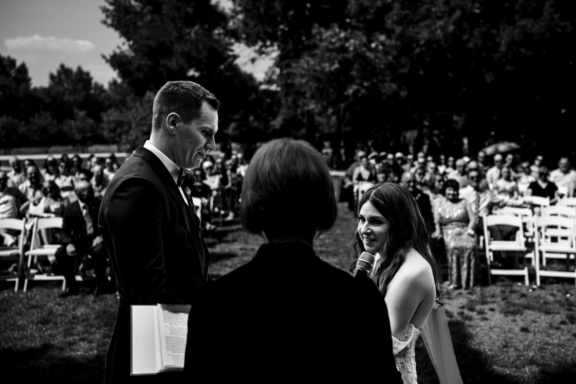 At Ashgrove Acres, a couple stands before an officiant with guests seated behind.