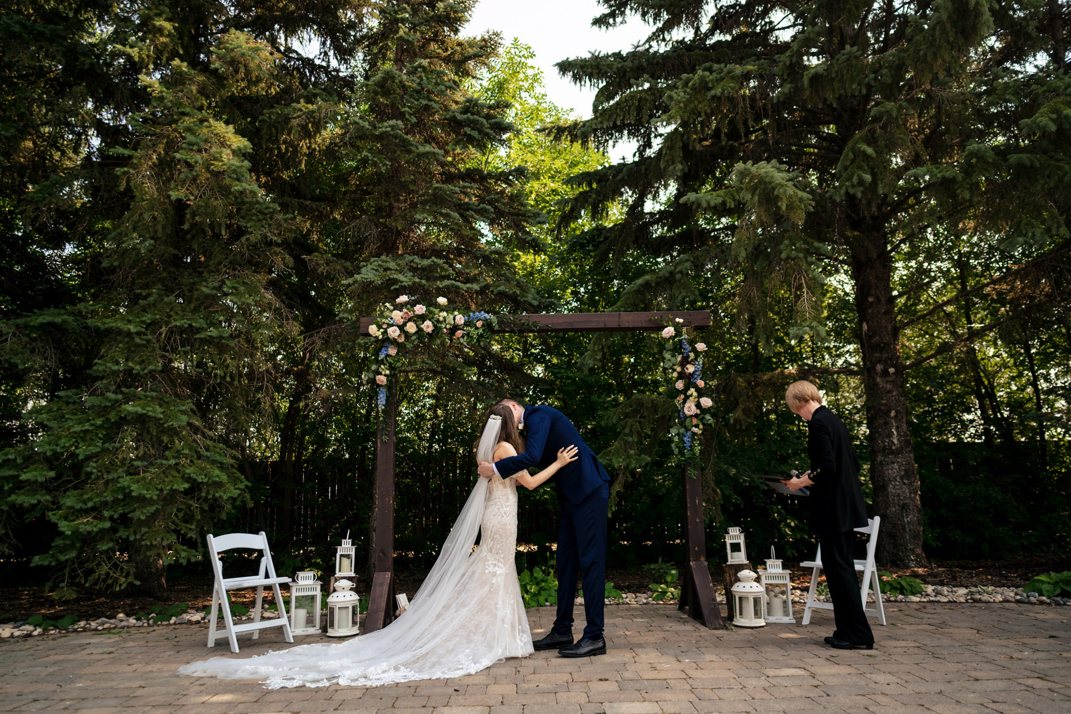 Couple kissing at an Ashgrove Acres wedding, surrounded by trees and lanterns.