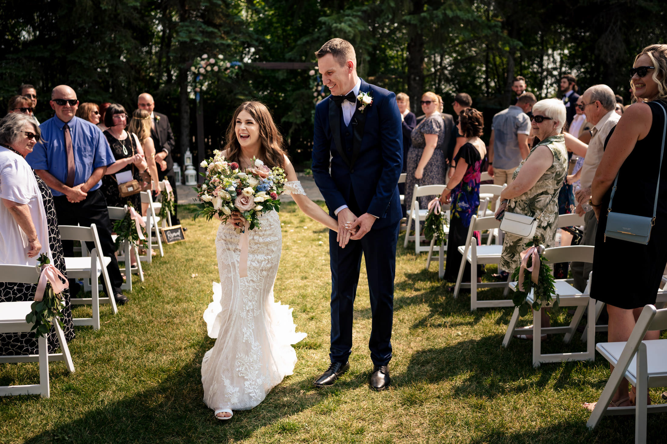 The bride and groom walk down the aisle at Ashgrove Acres, surrounded by smiling guests.