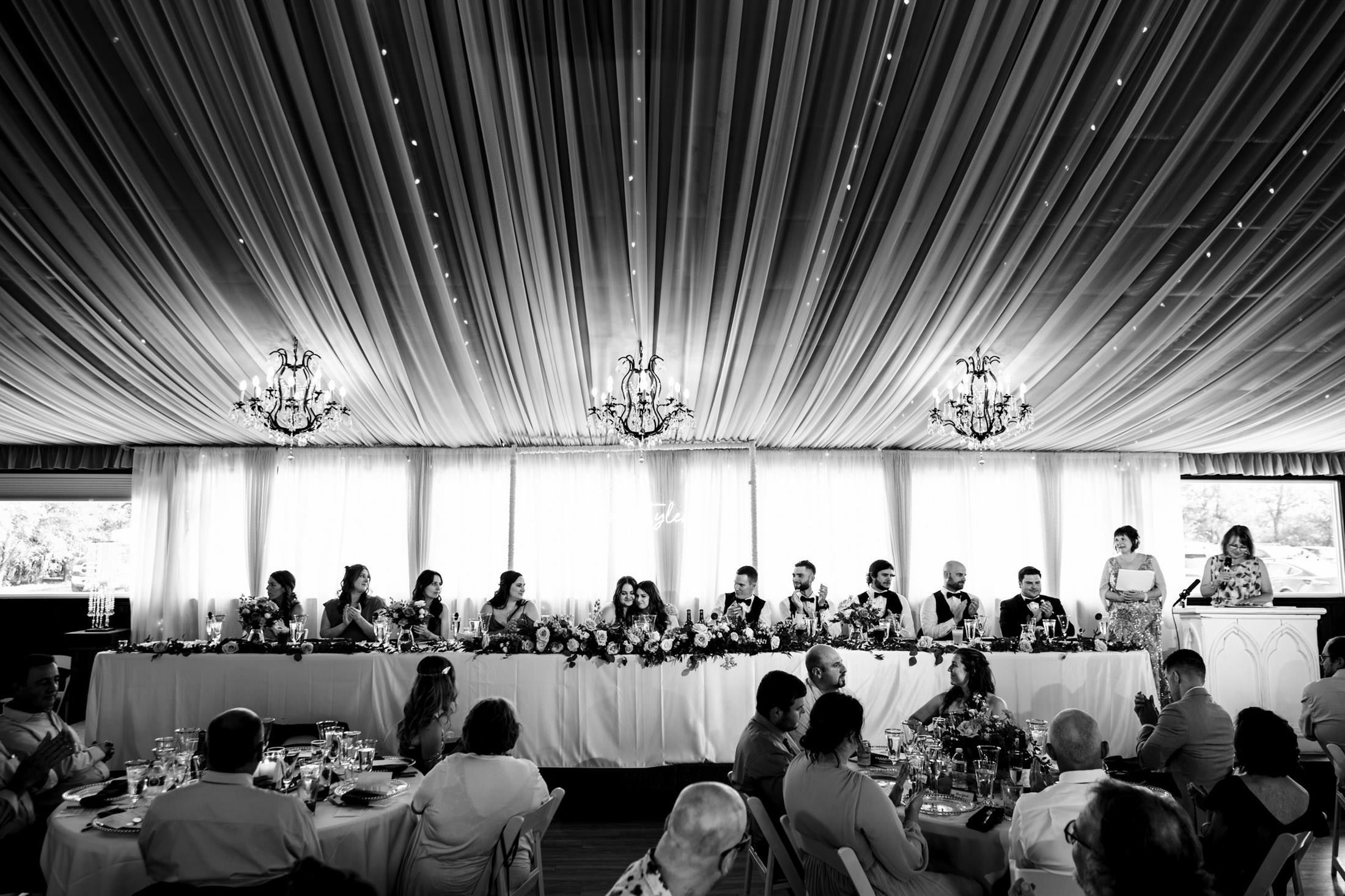 Guests seated at a long table under a draped ceiling at an Ashgrove Acres wedding.
