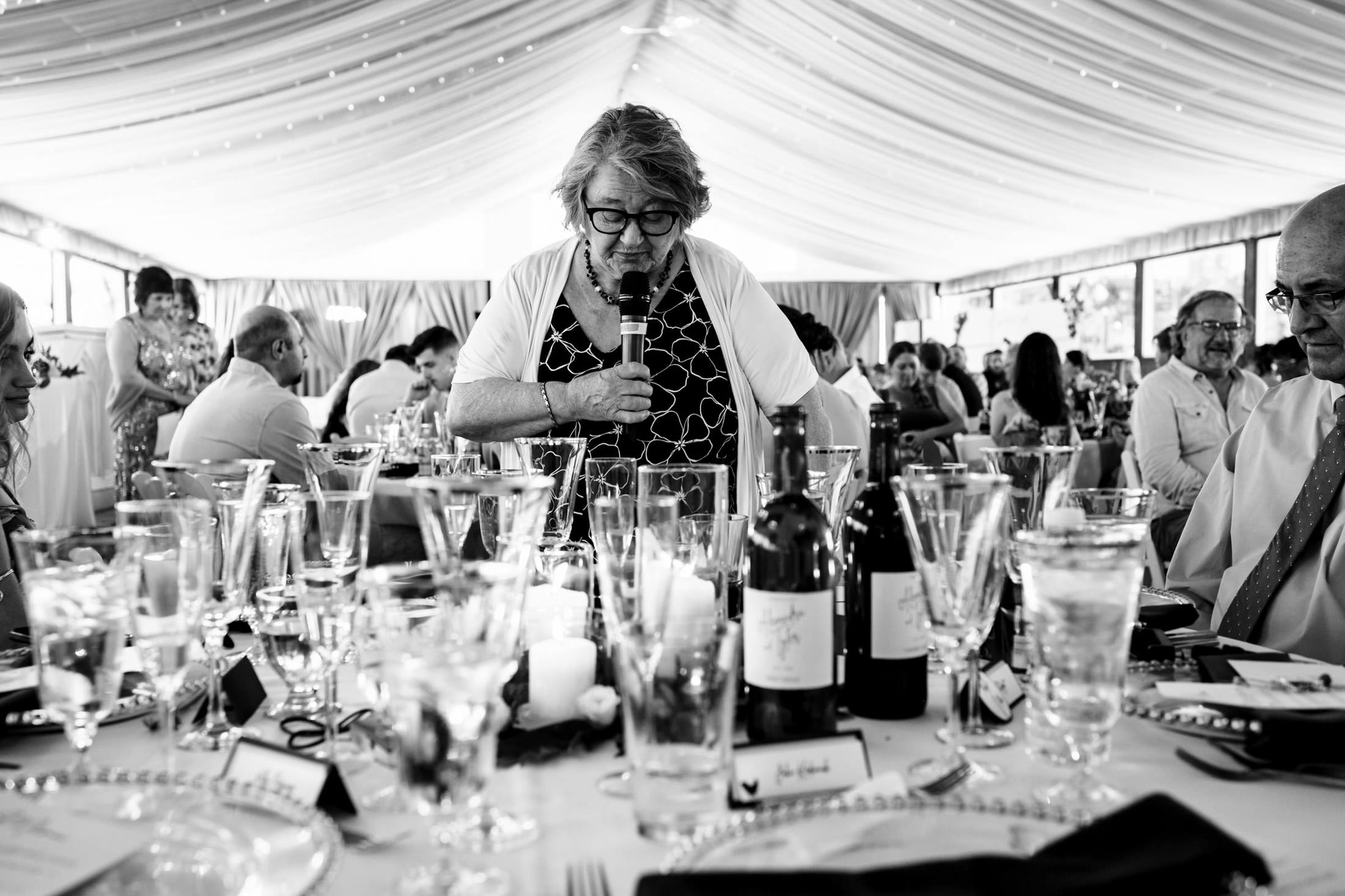 A woman speaks at an Ashgrove Acres wedding with elegantly set tables.