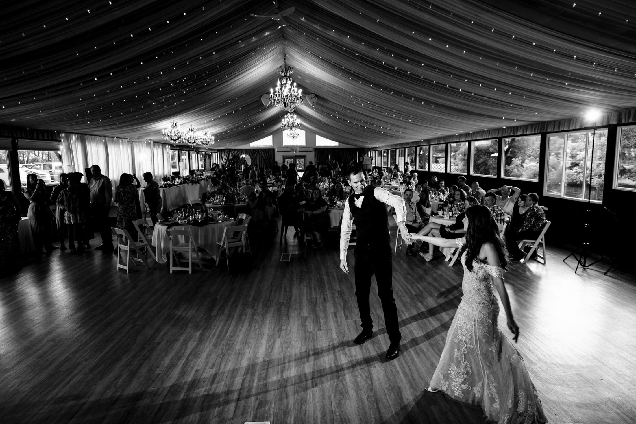 A couple dances at Ashgrove Acres, under twinkling lights in a tent filled with guests.