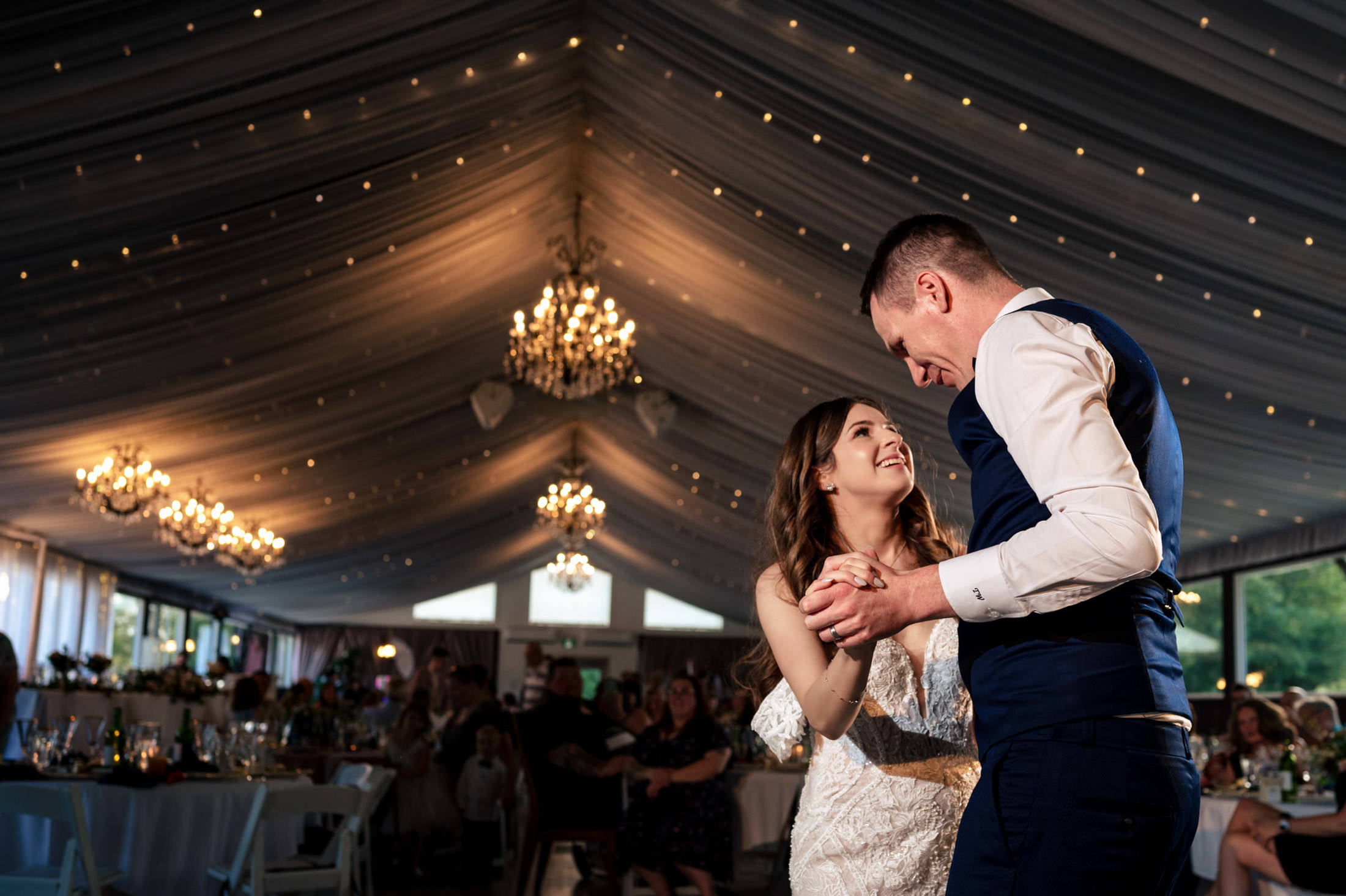 A couple shares a romantic dance at the elegant, warmly lit Ashgrove Acres reception hall.