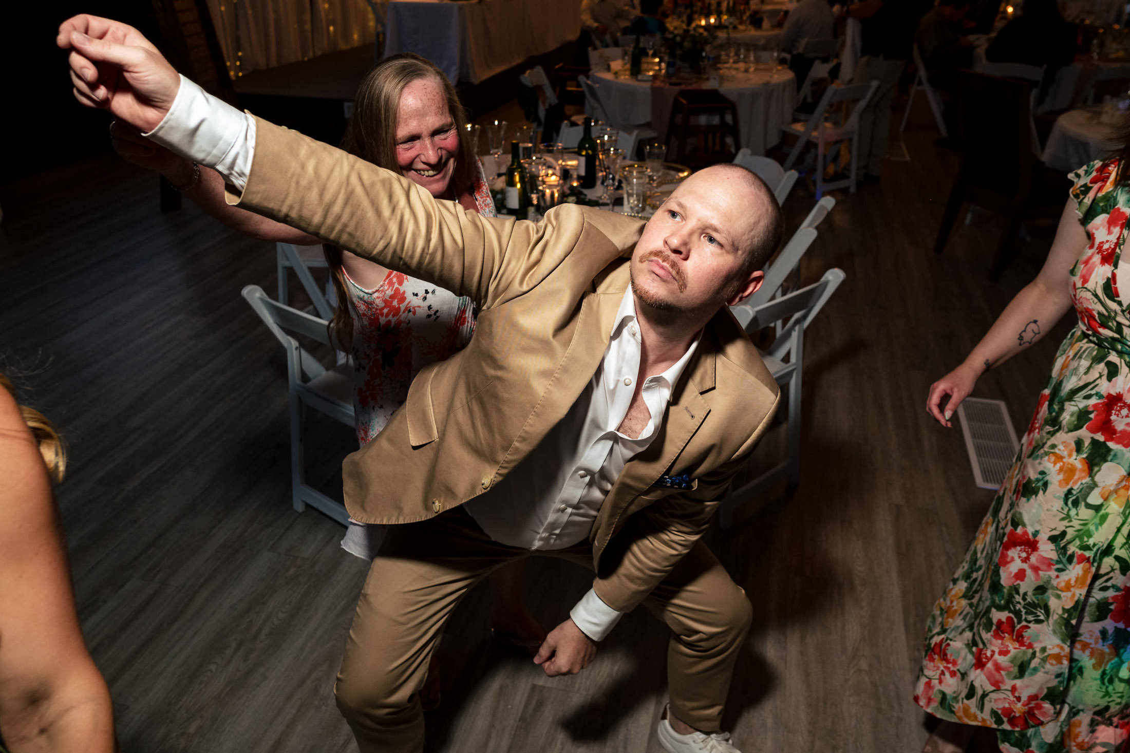 Person in a tan suit strikes a pose while dancing at an Ashgrove Acres wedding.