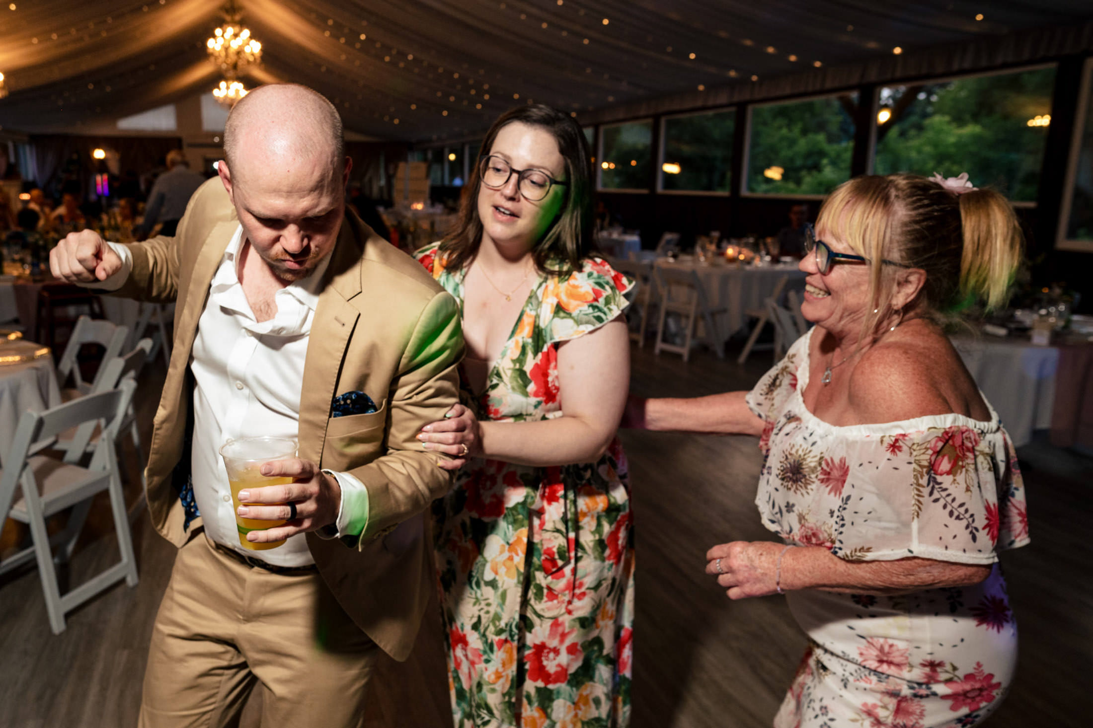 Three people dancing joyfully at an Ashgrove Acres Wedding reception.