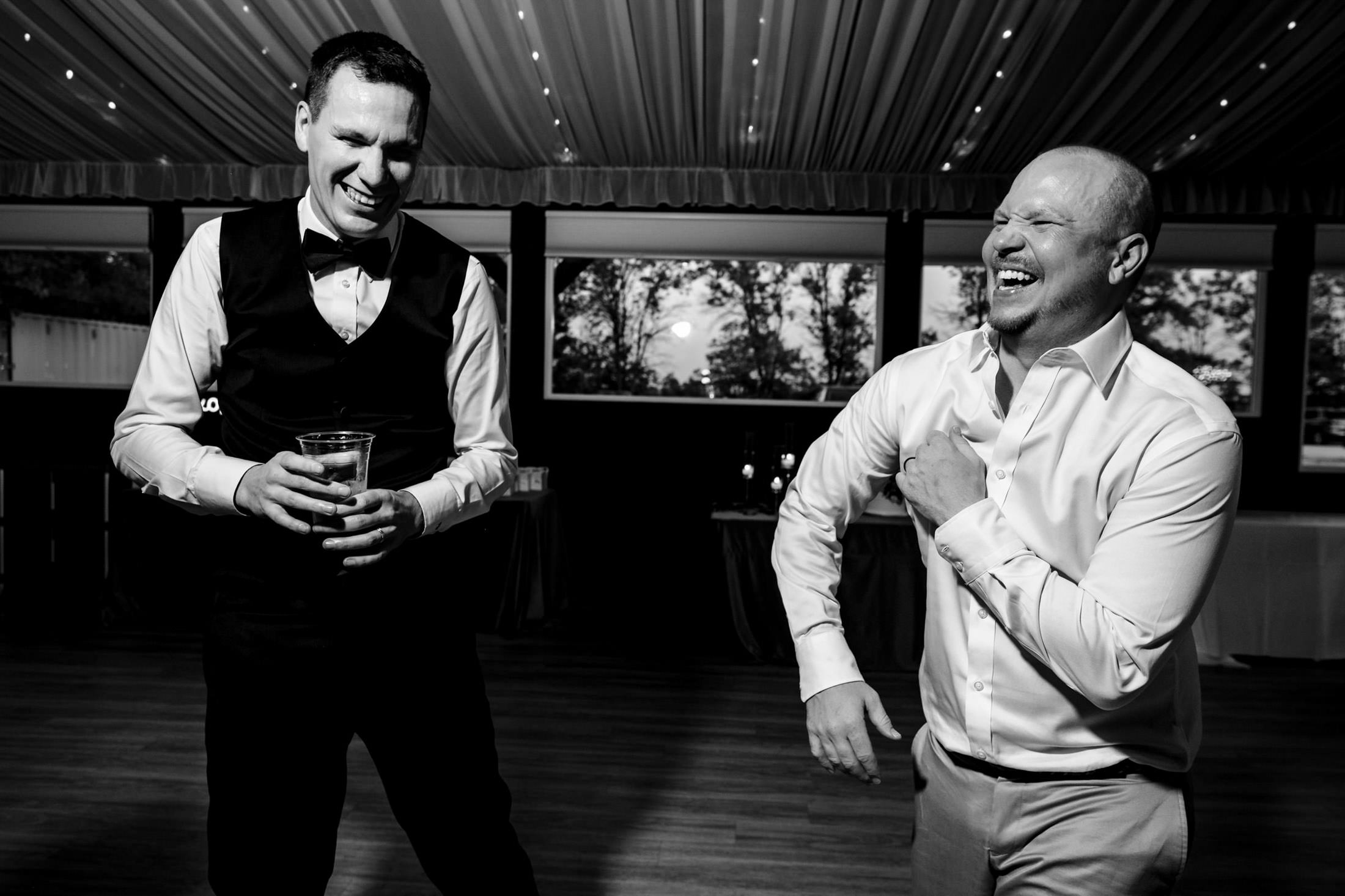Two men laughing and dancing at an Ashgrove Acres Wedding with draped ceiling.