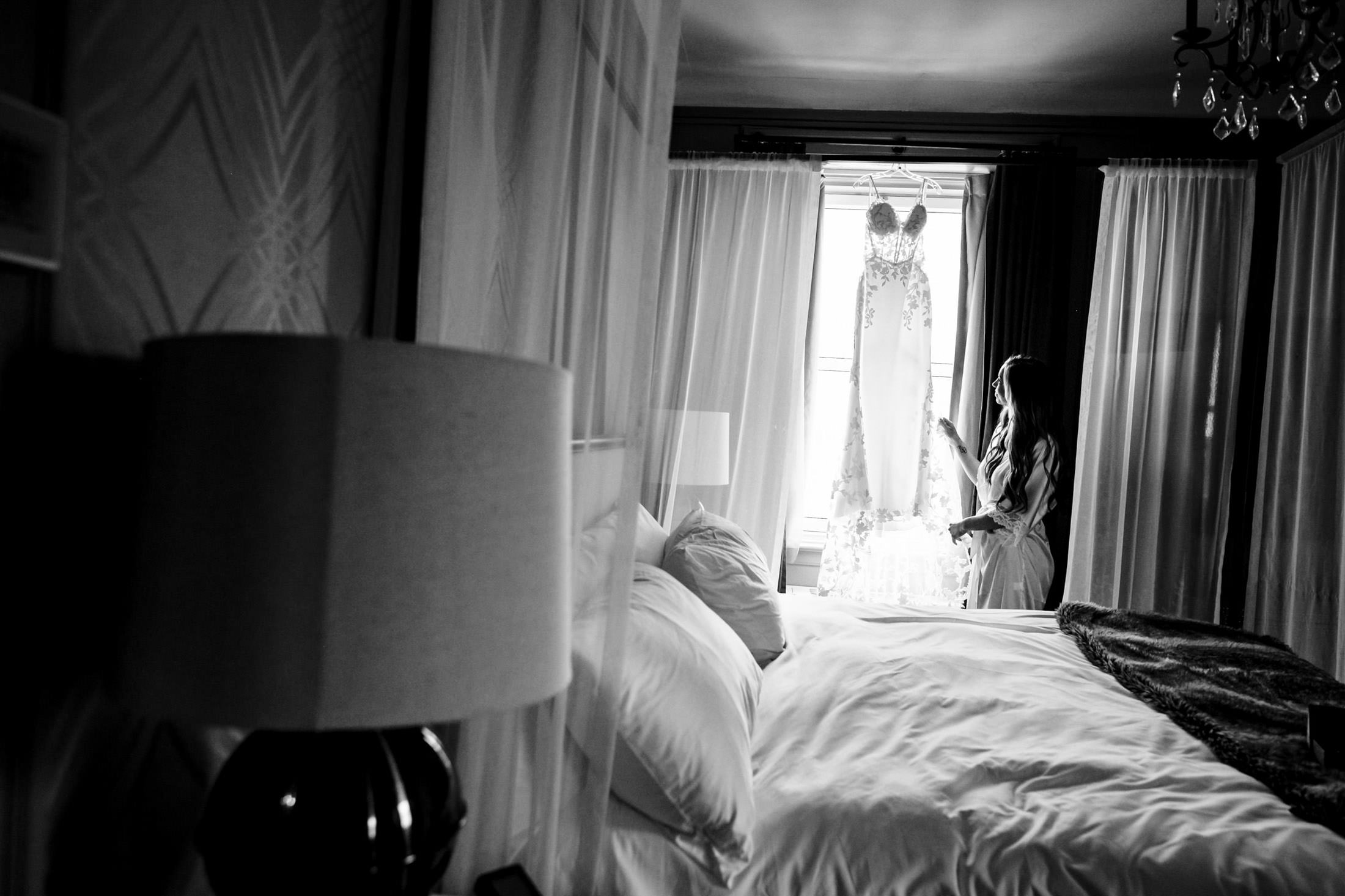 Italian elegance: Black and white image of a woman admiring a wedding dress in Winnipeg.