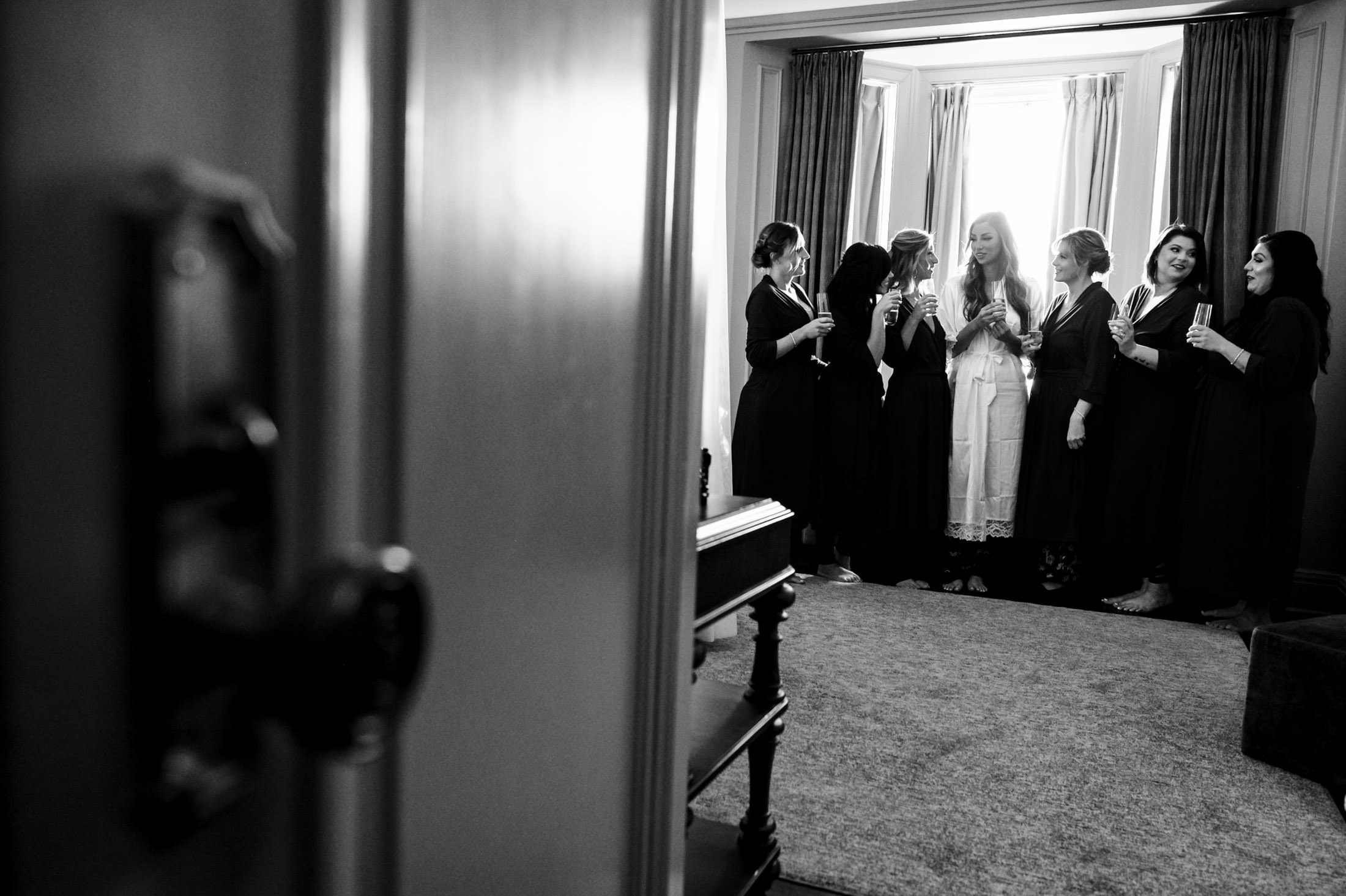 Bride and bridesmaids at an Italian wedding, smiling through a slightly open door.