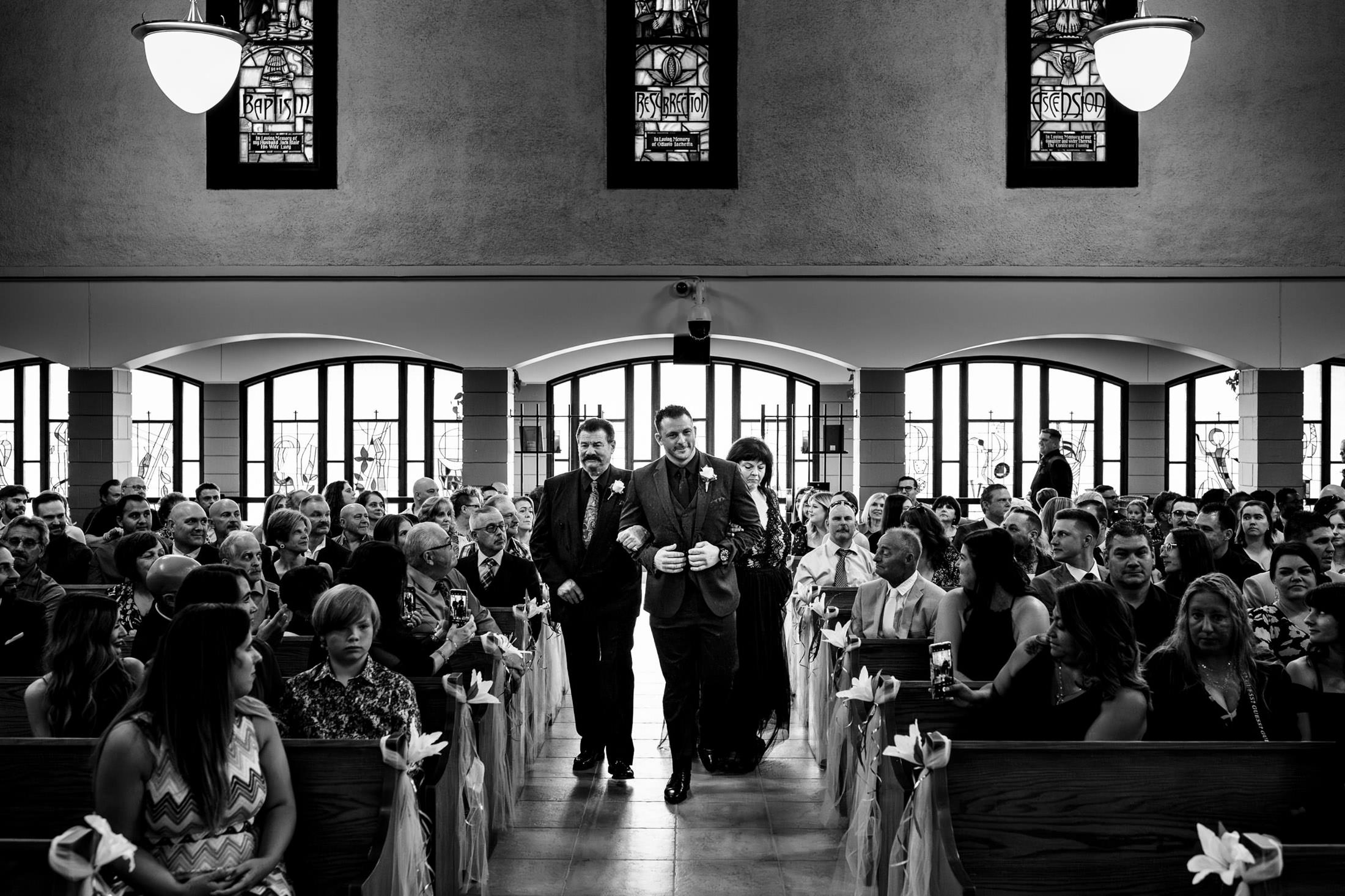 At an Italian wedding in Winnipeg, a groom walks down the aisle with two people.