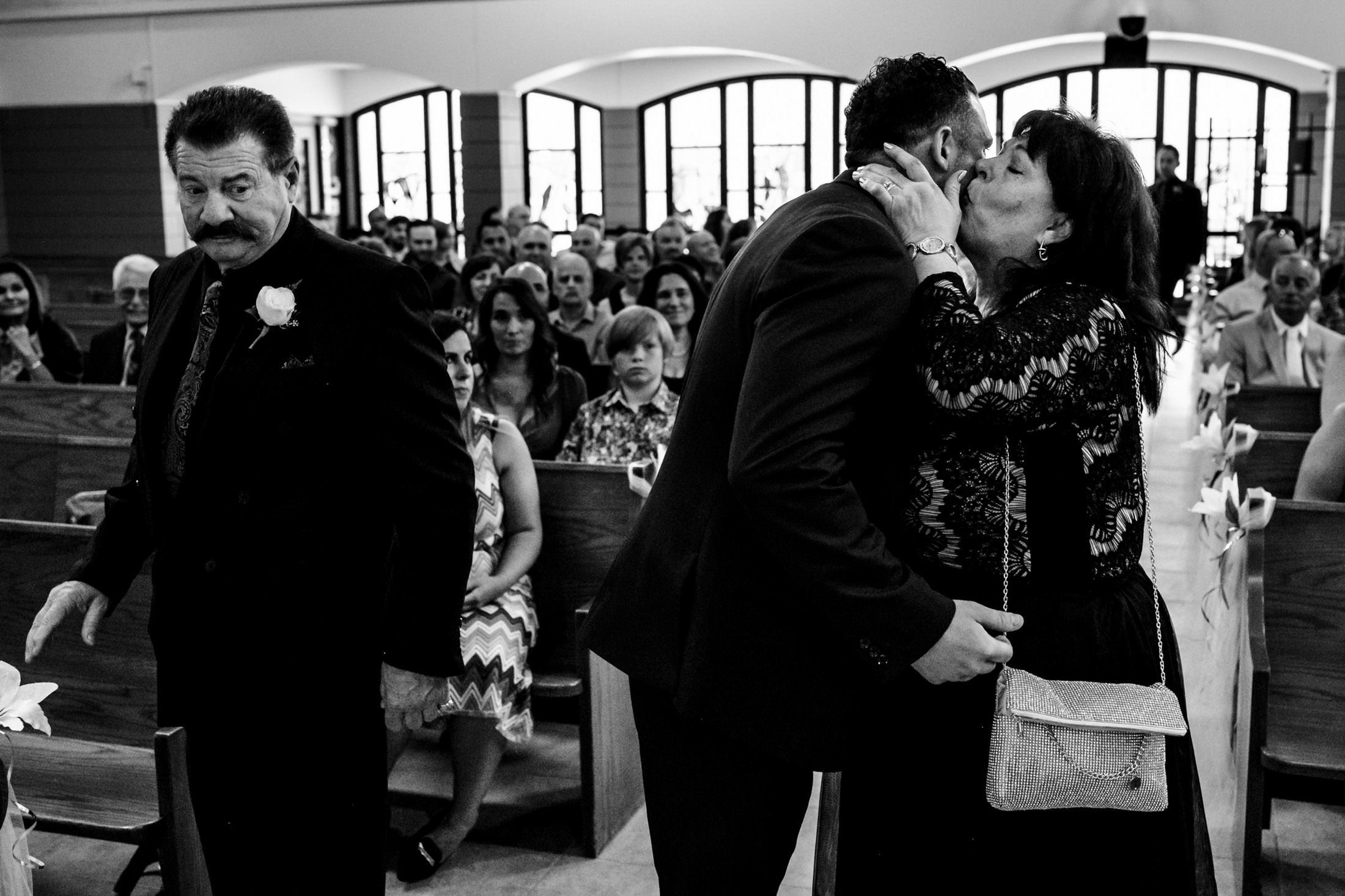 A woman kisses a man at an Italian wedding in Winnipeg, as another man walks away.